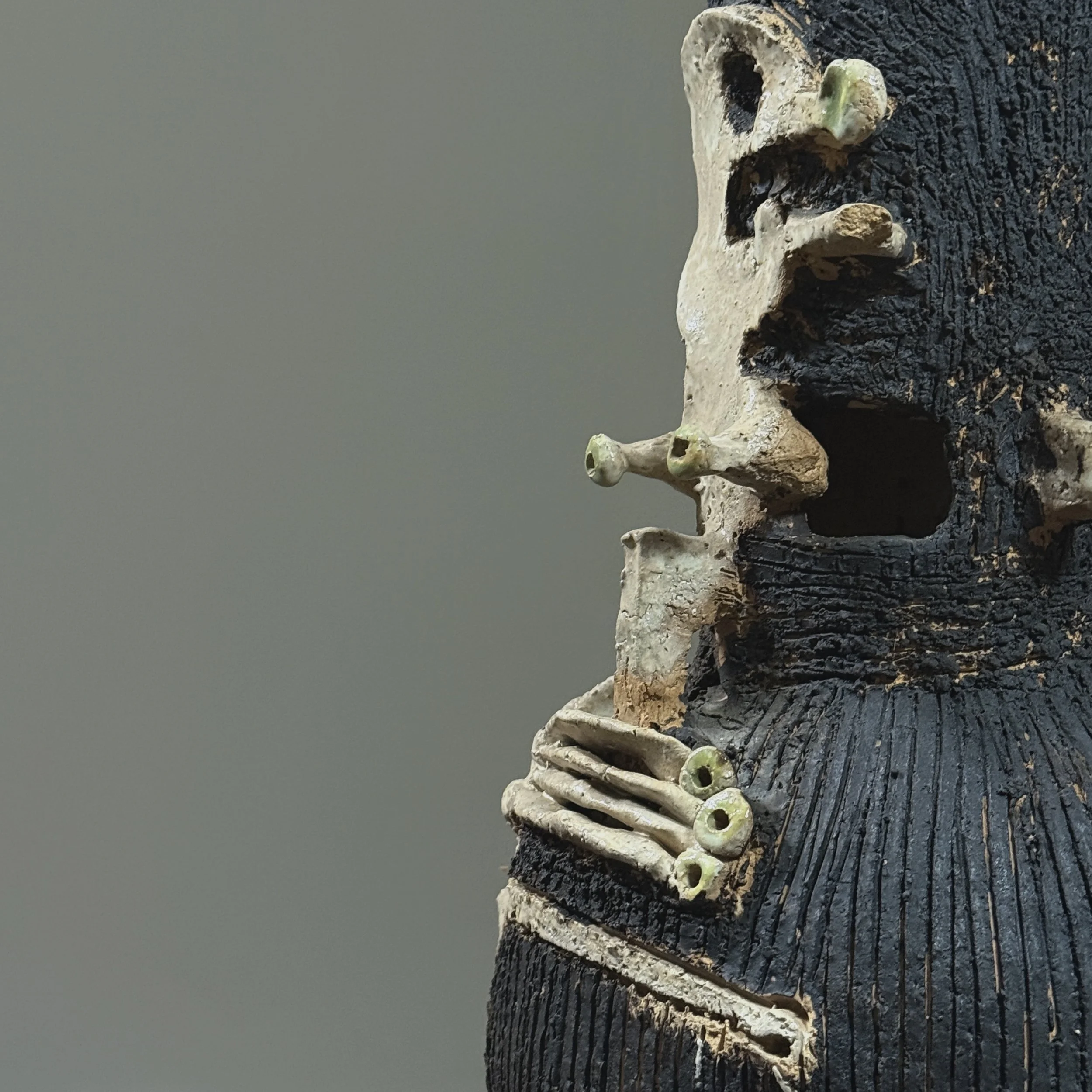 Close-up of the main applied sculptural element resembling a skull face.