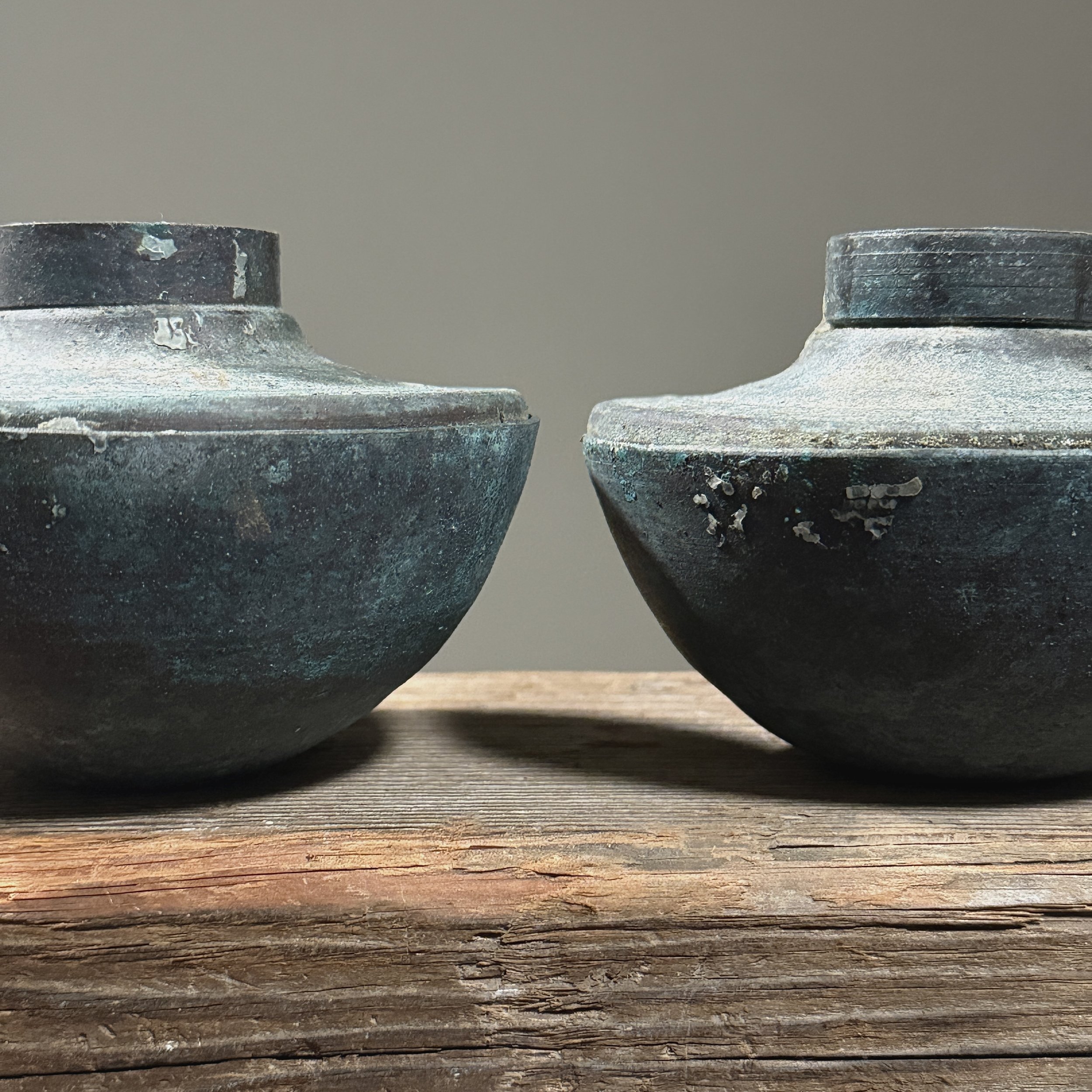 Close-up of textured surface on one Brutalist candle holder showing layered blue-green patina.