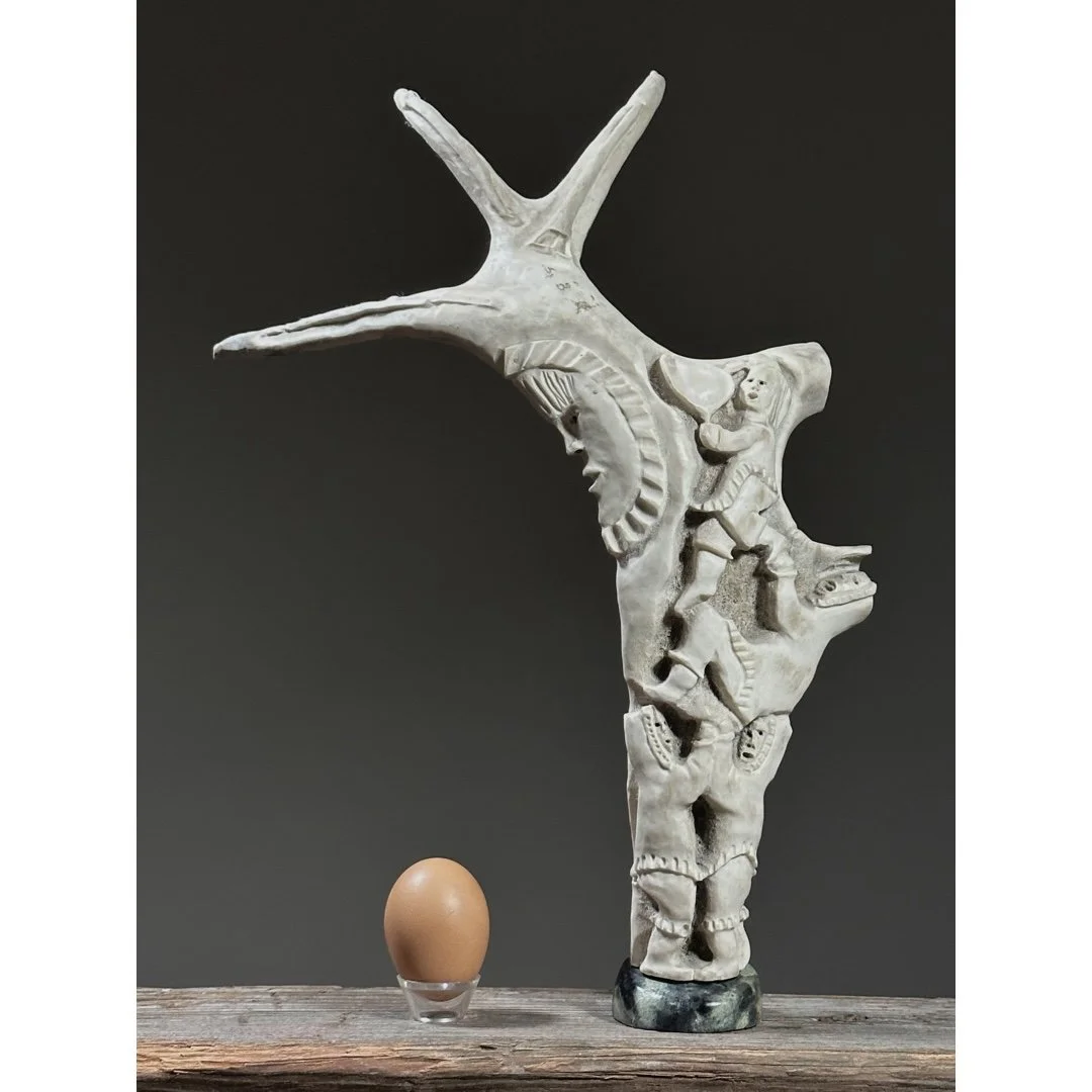 Full view of a vintage Inuit folk art antler sculpture with figures and moon with an egg for size reference.