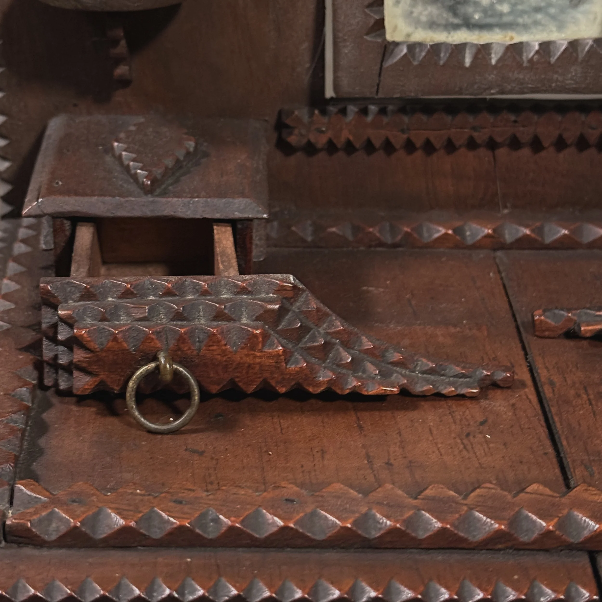 Winged upper drawers flanking the mirror on tramp art dresser