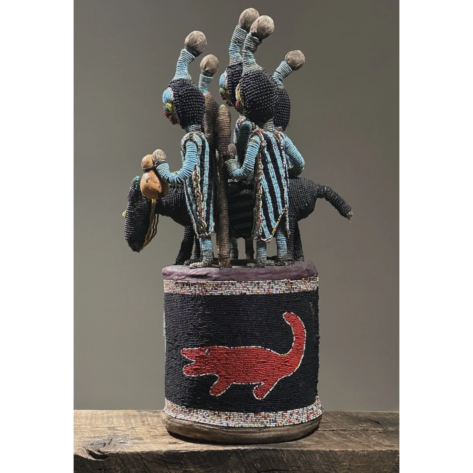 Side profile of a beaded Yoruba crown showing cylindrical base with crocodile and skull imagery