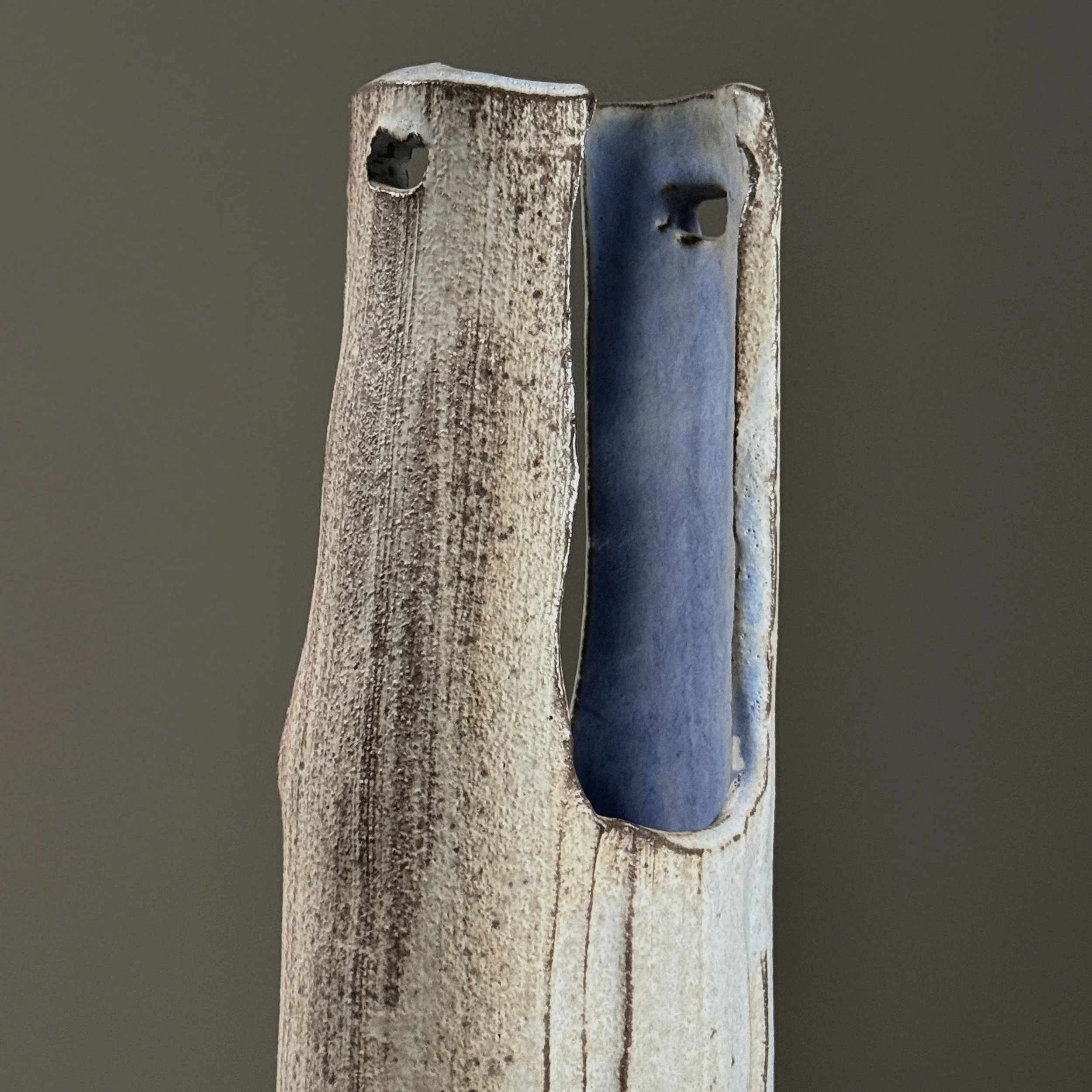 Close-up detail of wood-fired surface effects including pale blue streaks and speckled grey markings