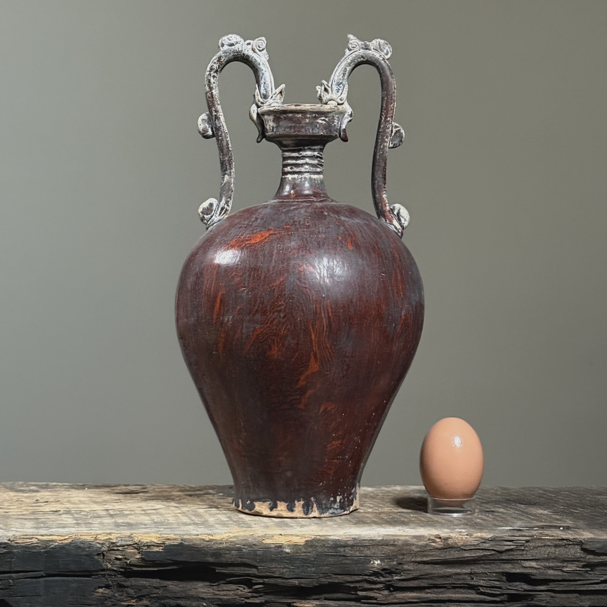 Chinese maroon wood-grain glazed pottery vase with egg for size reference.