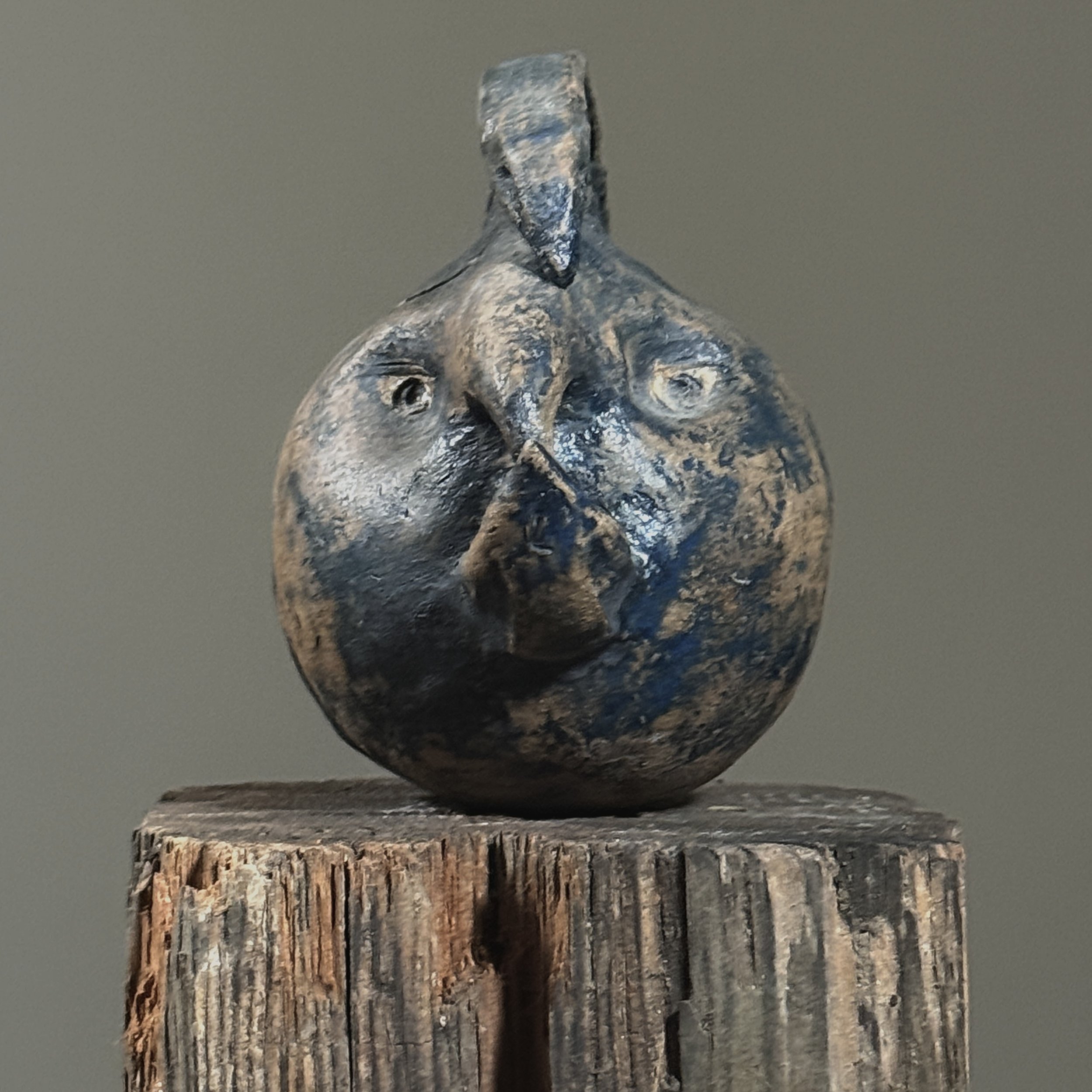 Wood-fired handmade teapot with sculptural facial features, front view