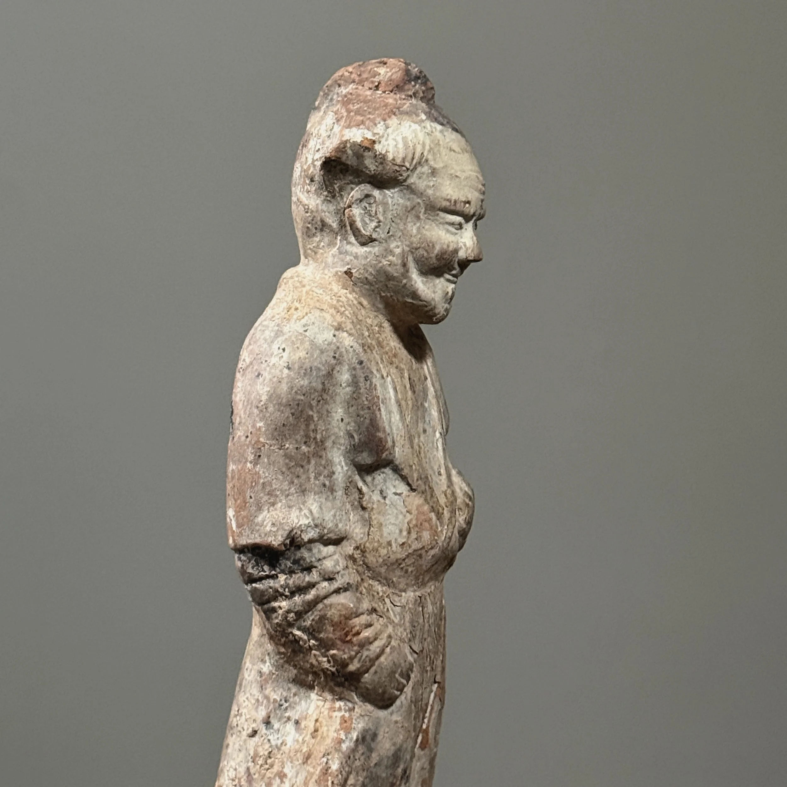 Three-quarter profile view showing the depth and posture of the mingqi sculpture.