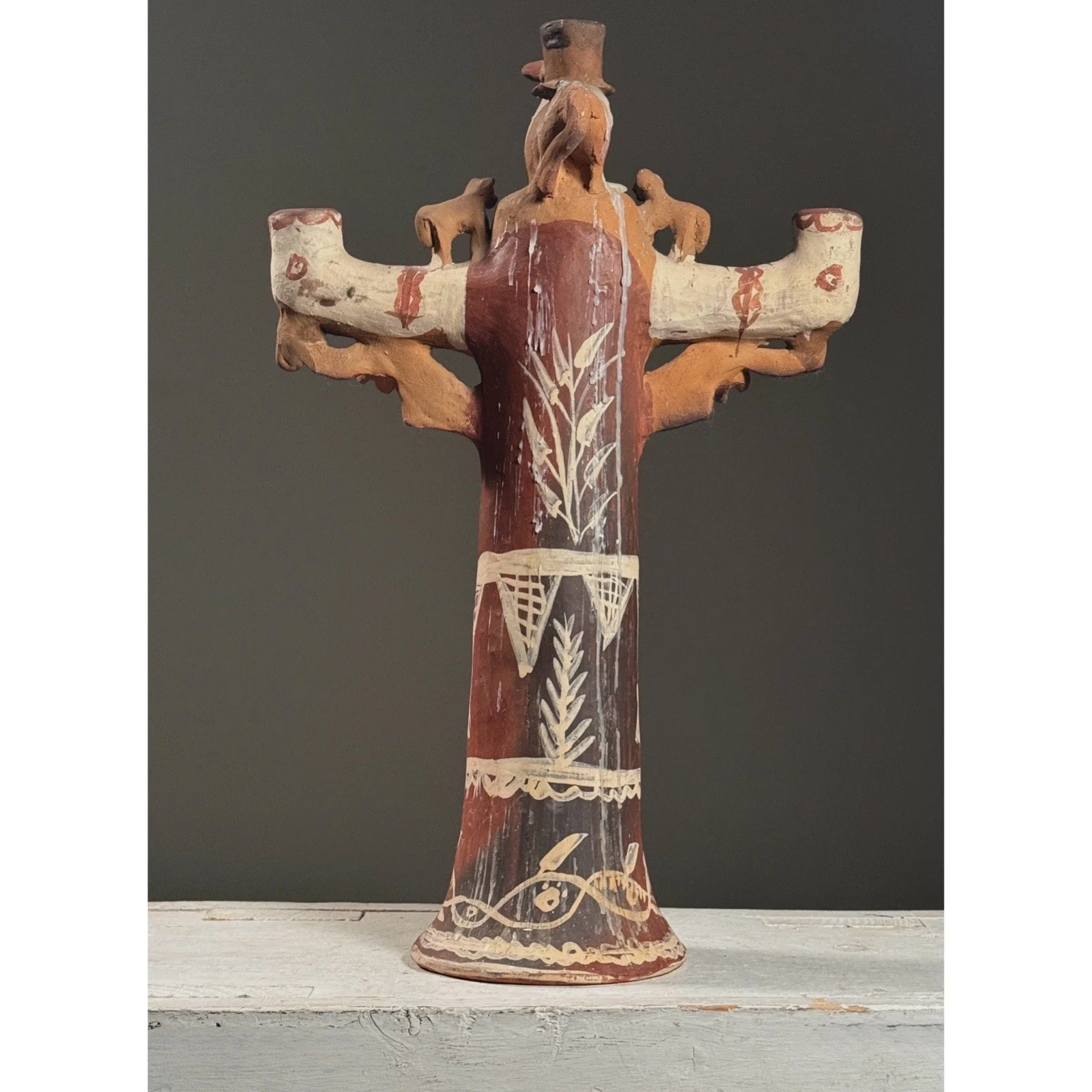 Rear view of a vintage folk art candelabra with visible wax residue dripping from historical use
