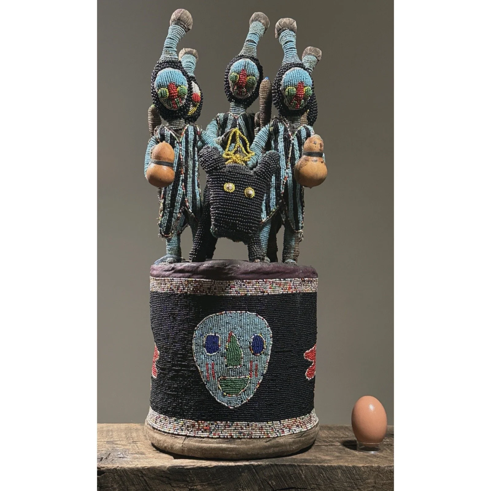 Full frontal view of a vintage Yoruba beaded ceremonial headdress with central equestrian figure With egg for size reference.