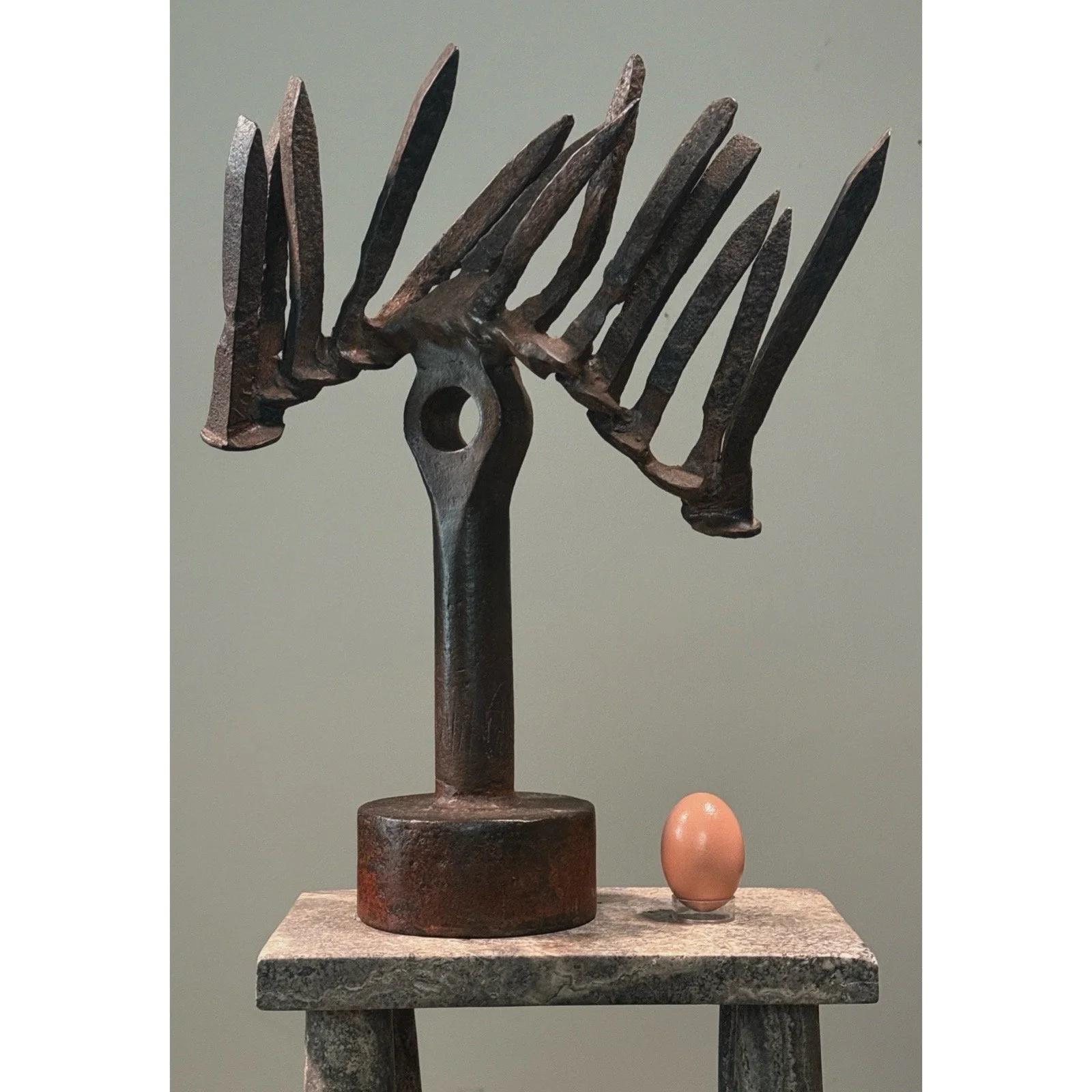 Vintage Brutalist abstract forged iron sculpture on white background with egg for size reference.