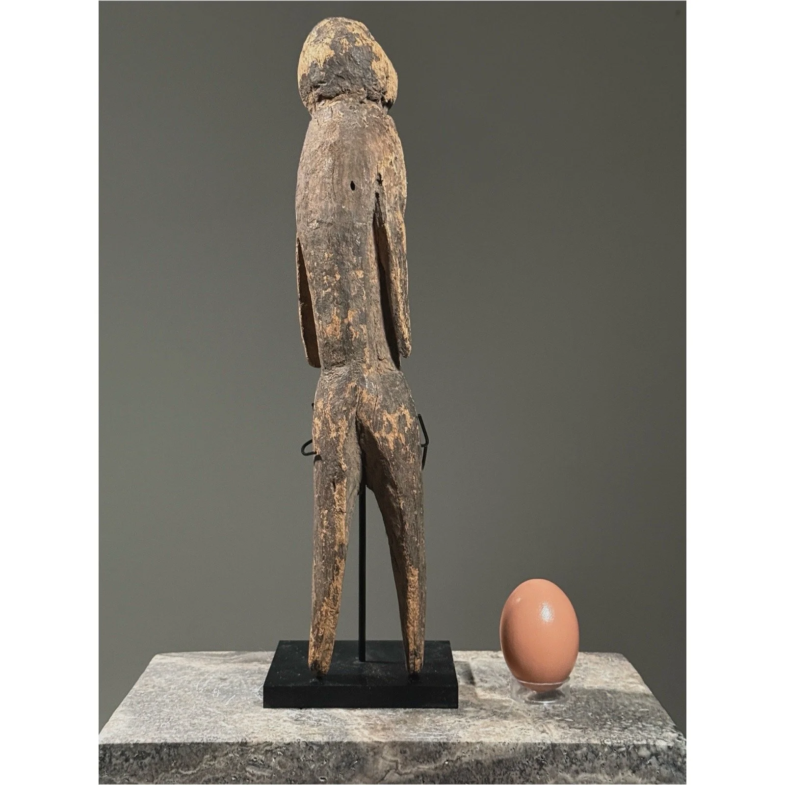 Rear view of a Moba tchitcheri figure showing hand-carved construction from a single piece of wood With egg for size reference.
