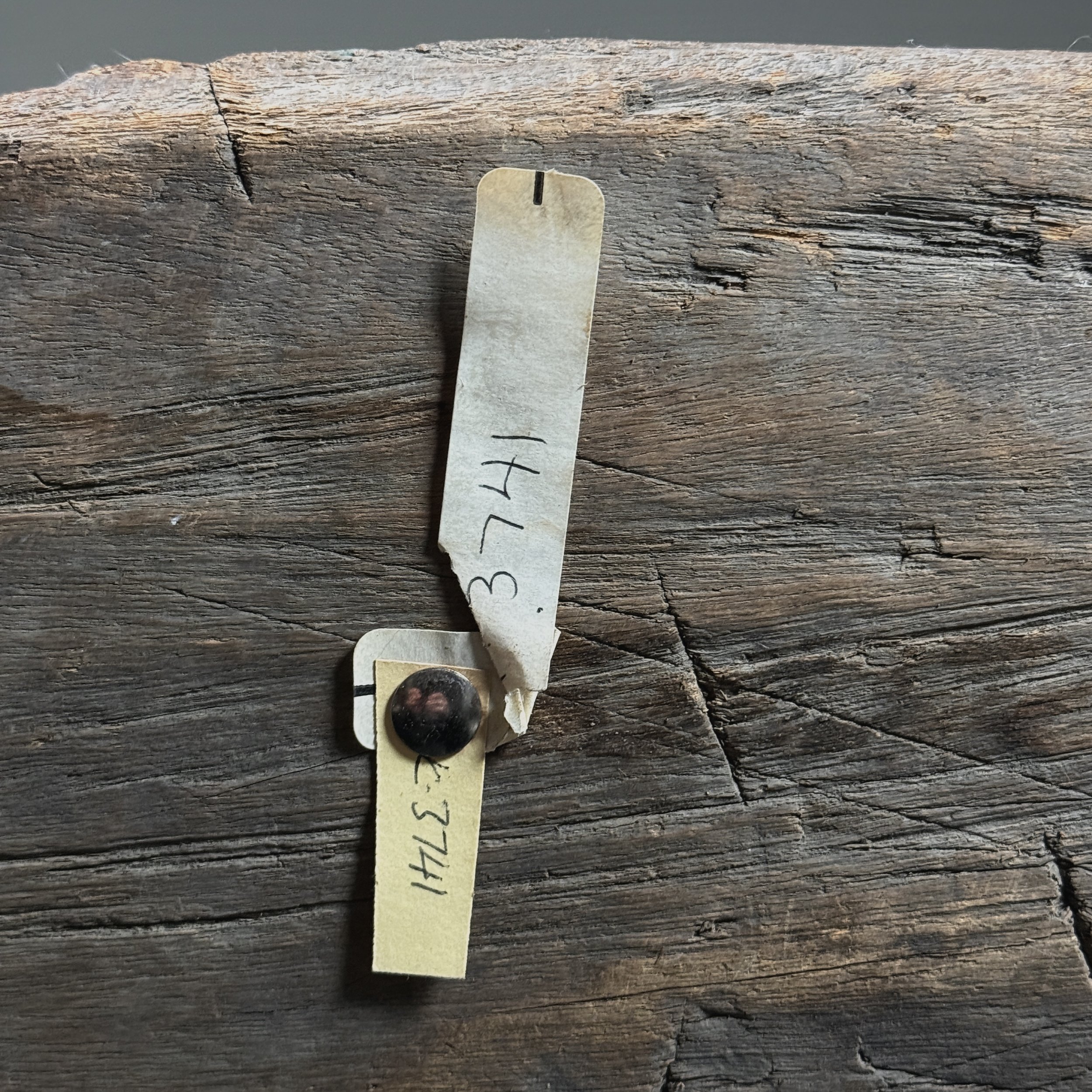 Detail of the original museum tags affixed to the underside of the stool
