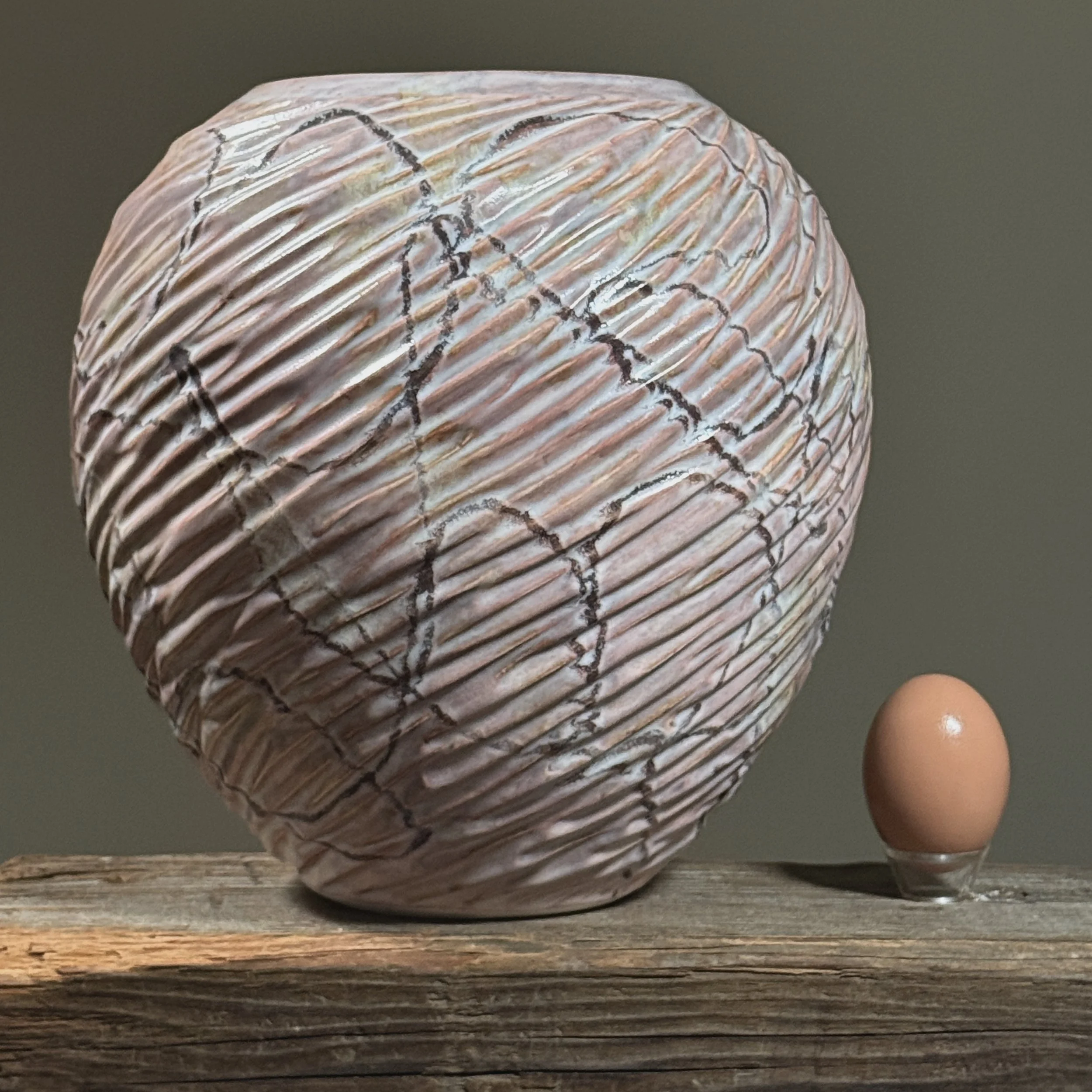 Pink ribbed ceramic vase with subtle gold highlights, mid-century Japanese design with egg for size reference.