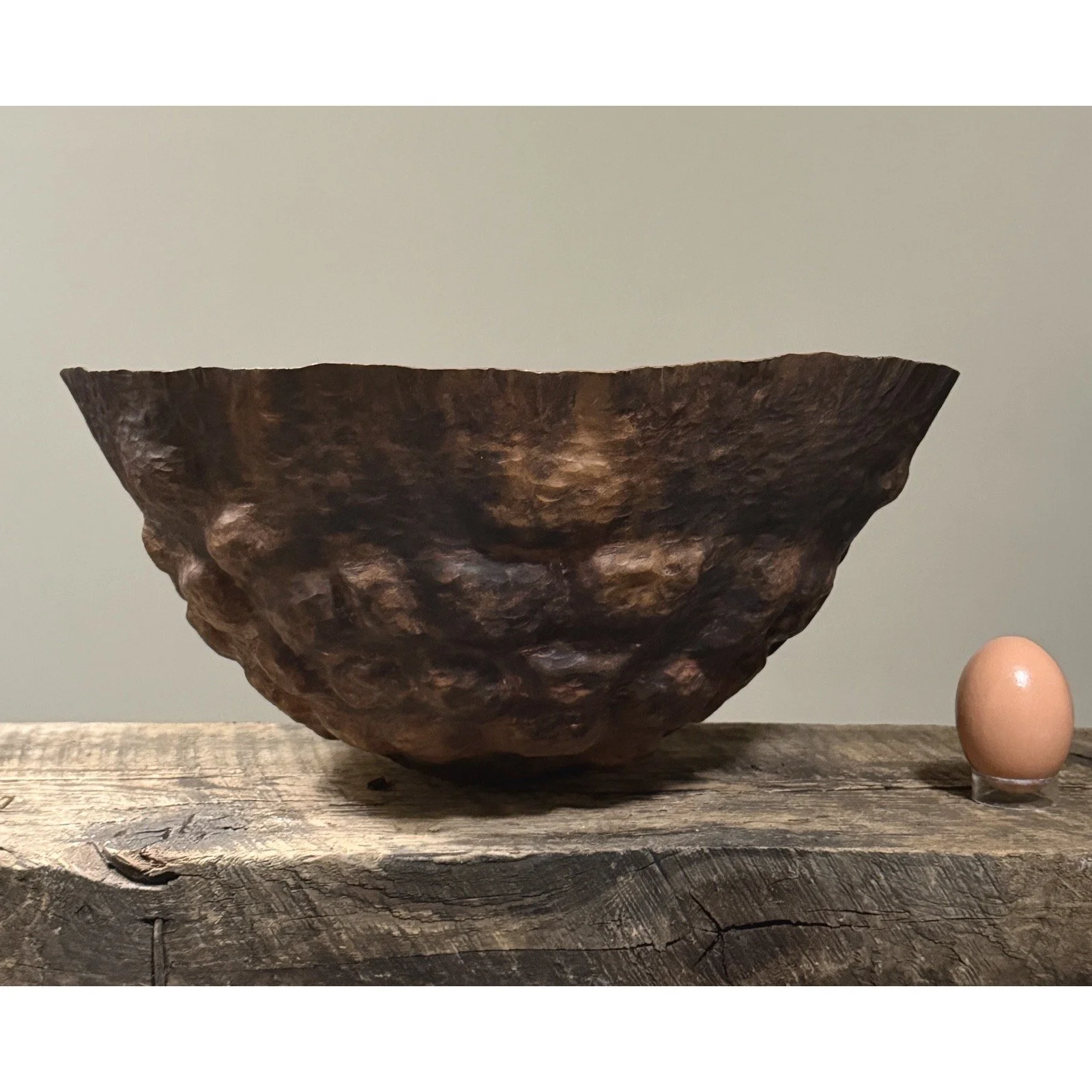 Side view showing the sculptural hammered texture and patina of Di Bona copper bowl with egg for size reference.