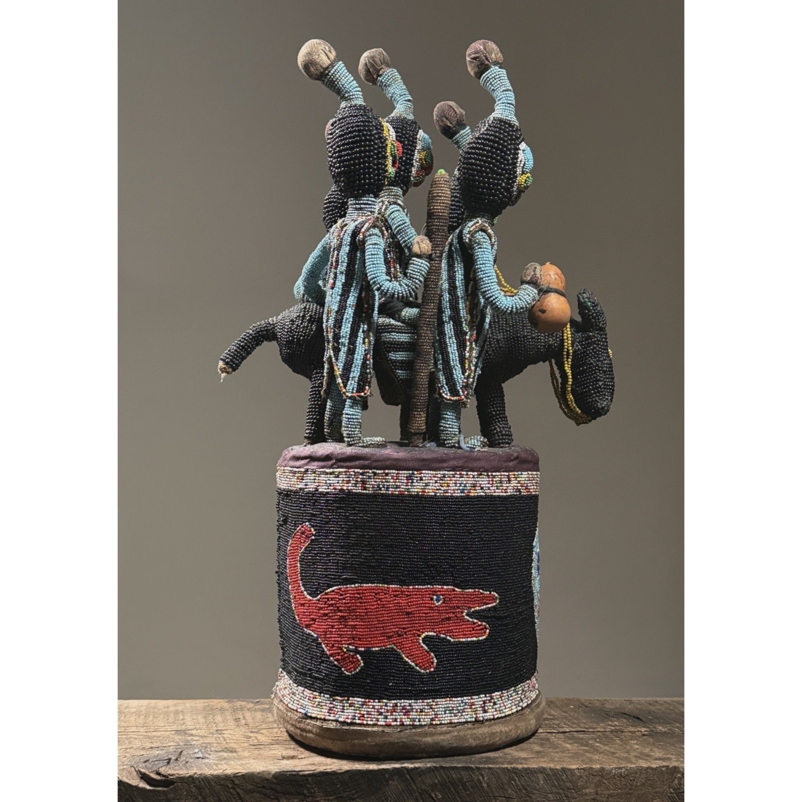 Side profile of a beaded Yoruba crown showing cylindrical base with crocodile and skull imagery