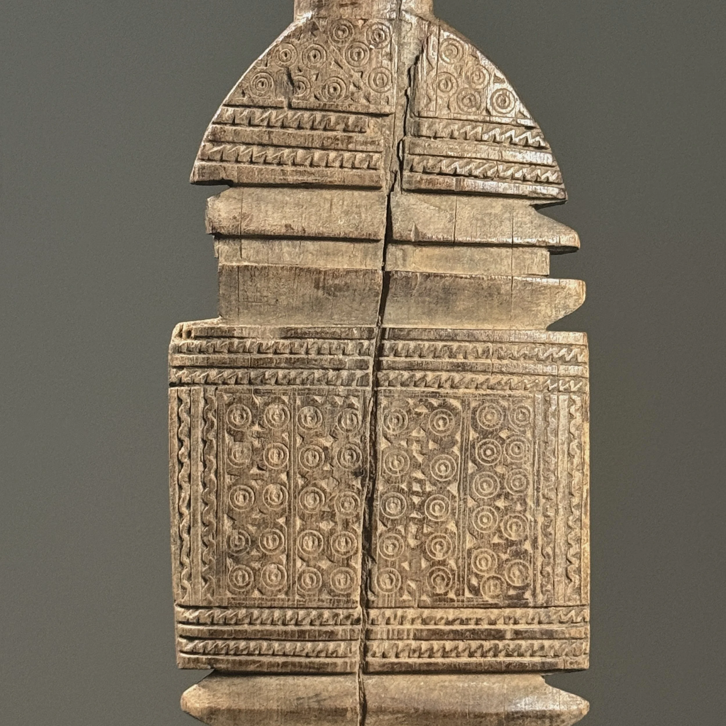 Detail of intricate incised swirling motifs on the wooden surface.