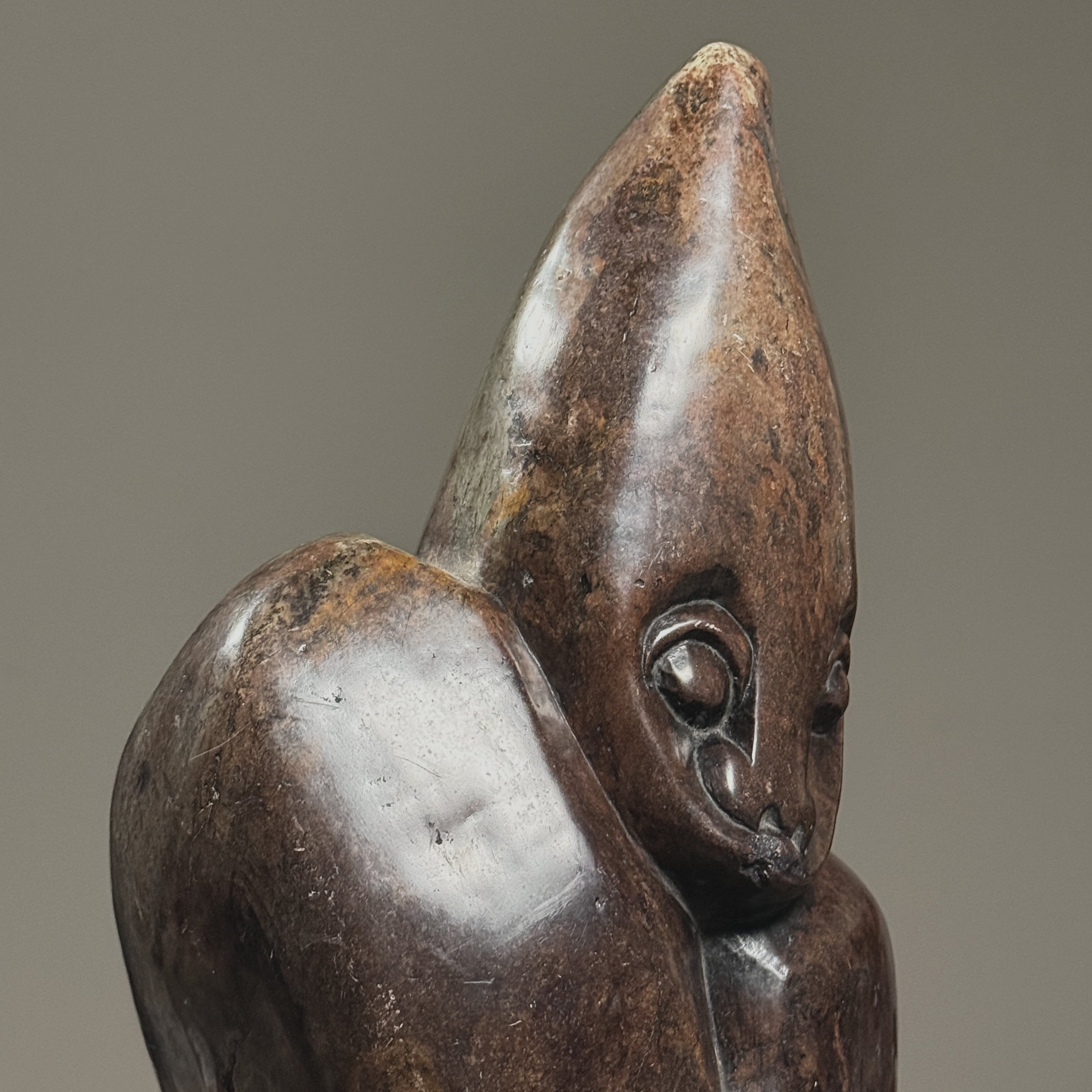 Three-quarter view of hand-carved abstract Zimbabwean sculpture showing smooth and textured stone surfaces.