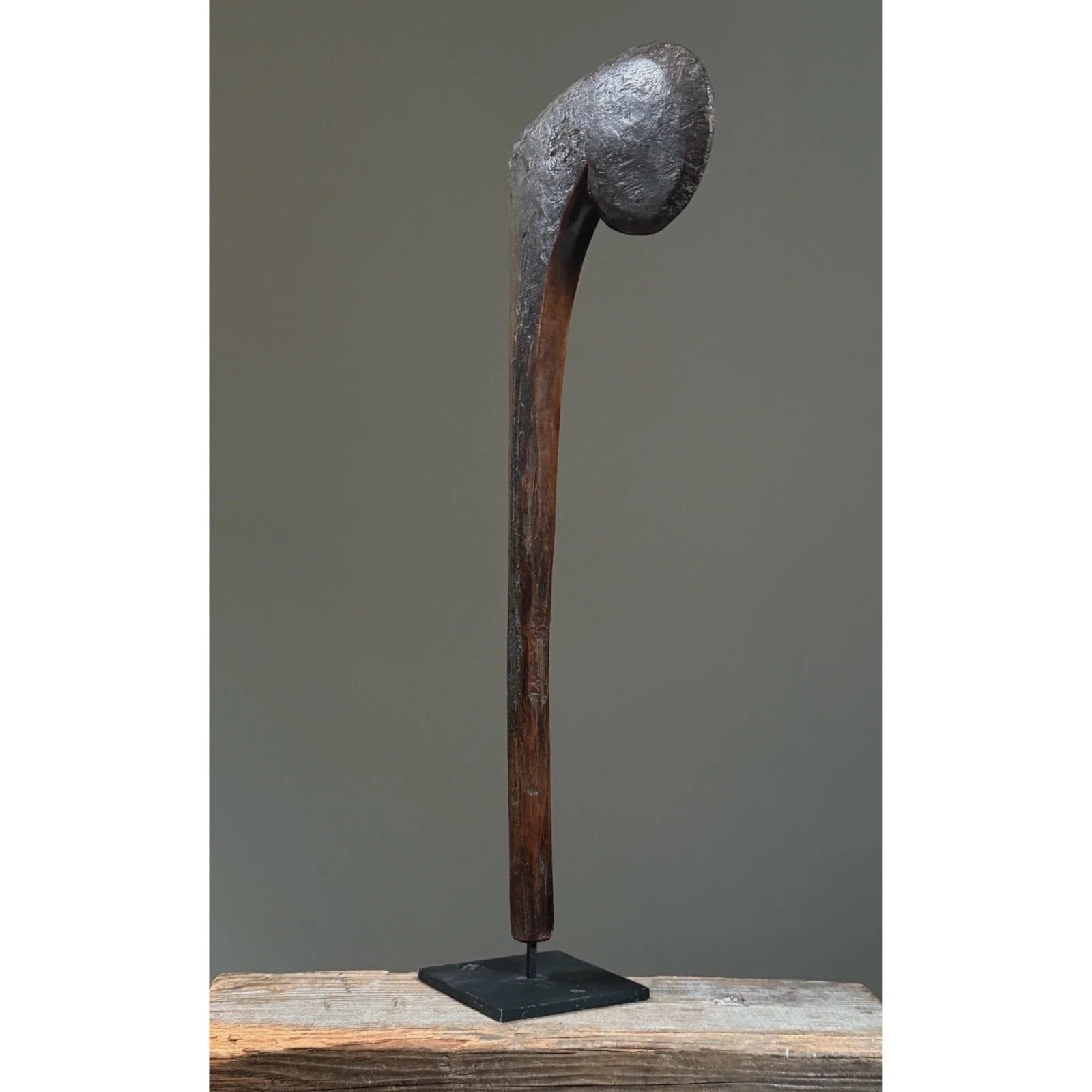 A hand-carved wooden ceremonial scepter from Burkina Faso, Bobo-style, on a black metal stand.