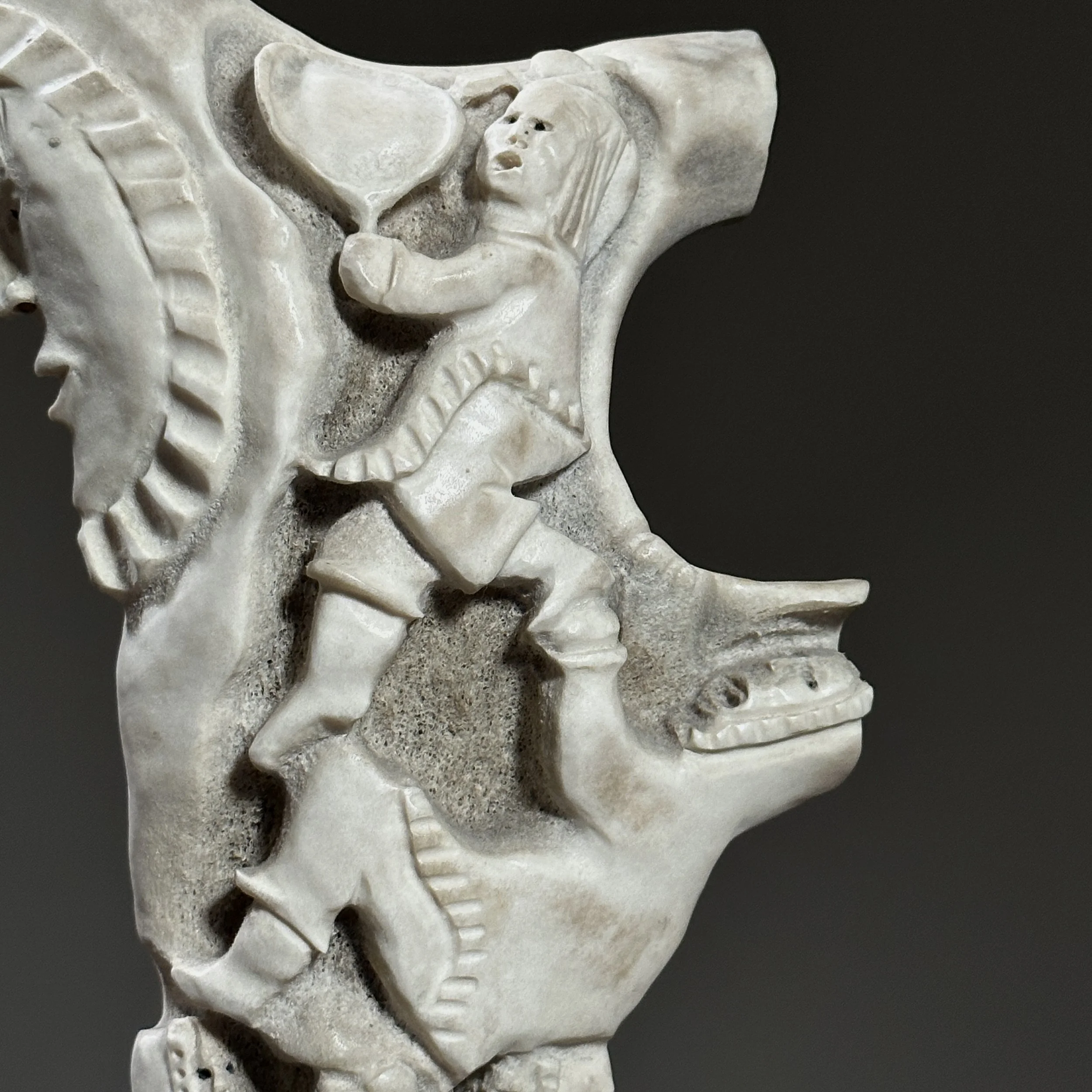 Detail of carved figures emerging from the antler form.