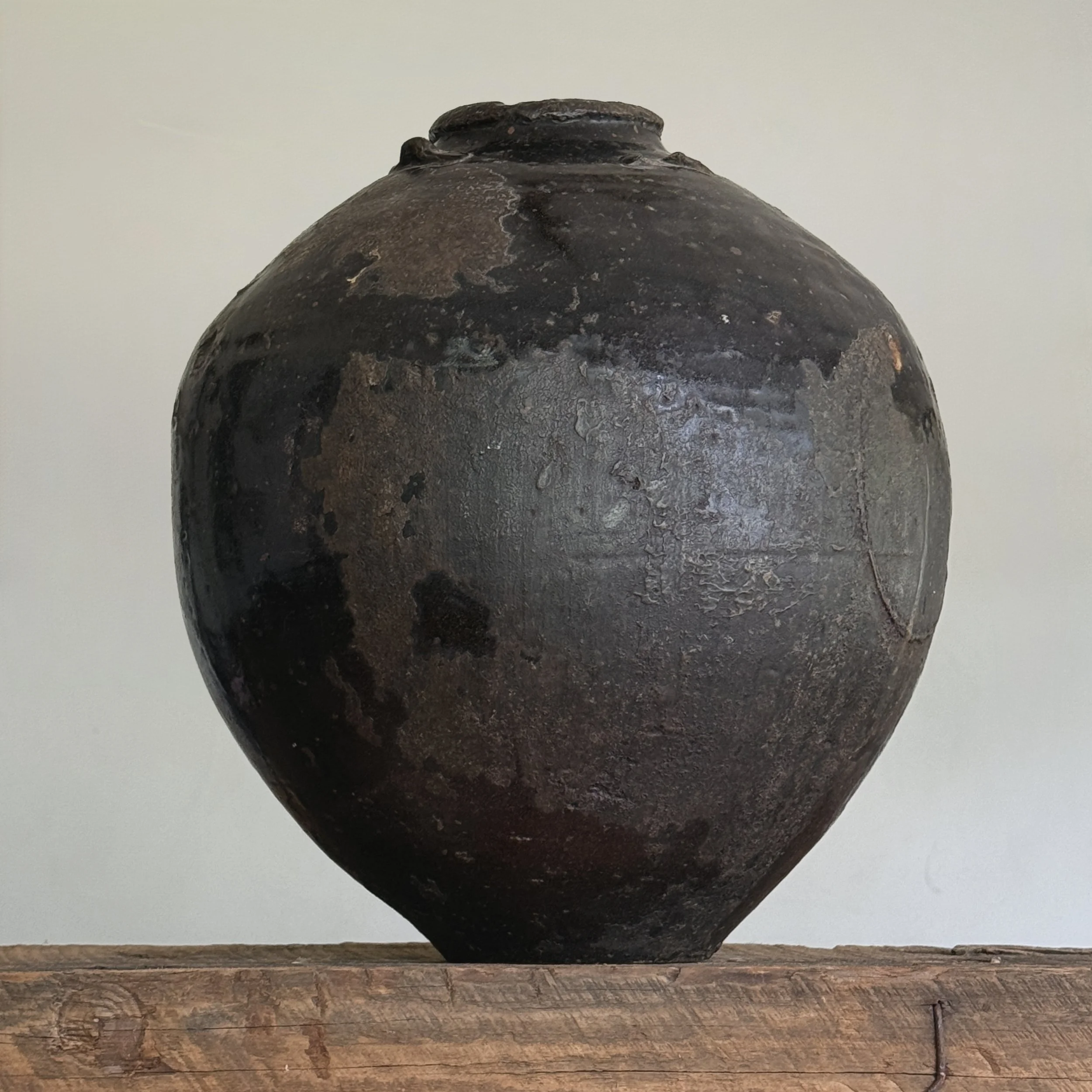 Full view of 17th century black-glazed ceramic storage vessel In daylight.