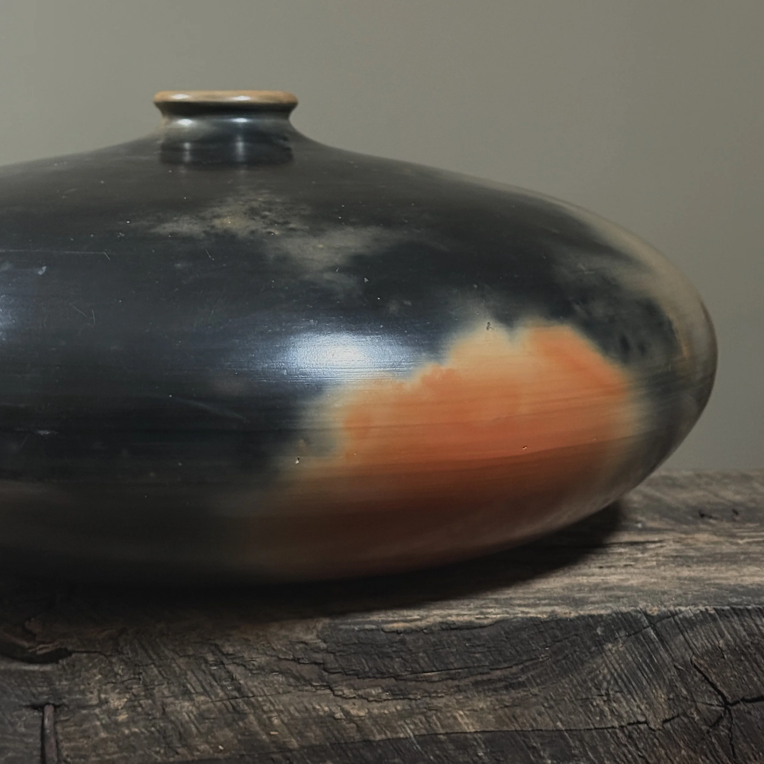 Detail of burnished orange and black surface on hand-turned vessel.