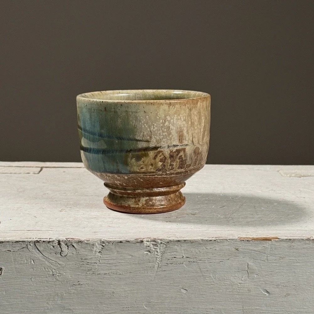 Front view of a vintage wood-fired yunomi with ash and turquoise glaze.