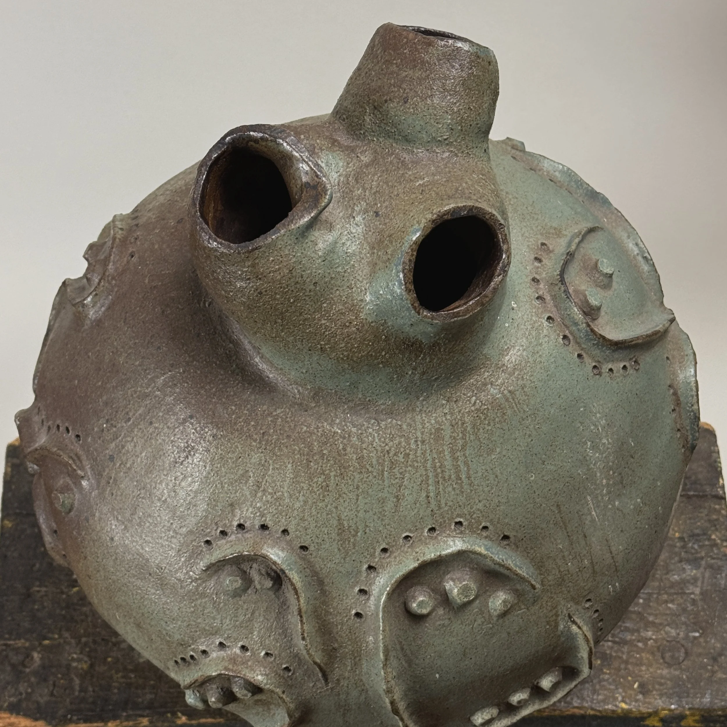 Organic modern ceramic vessel with three openings and textured surface.