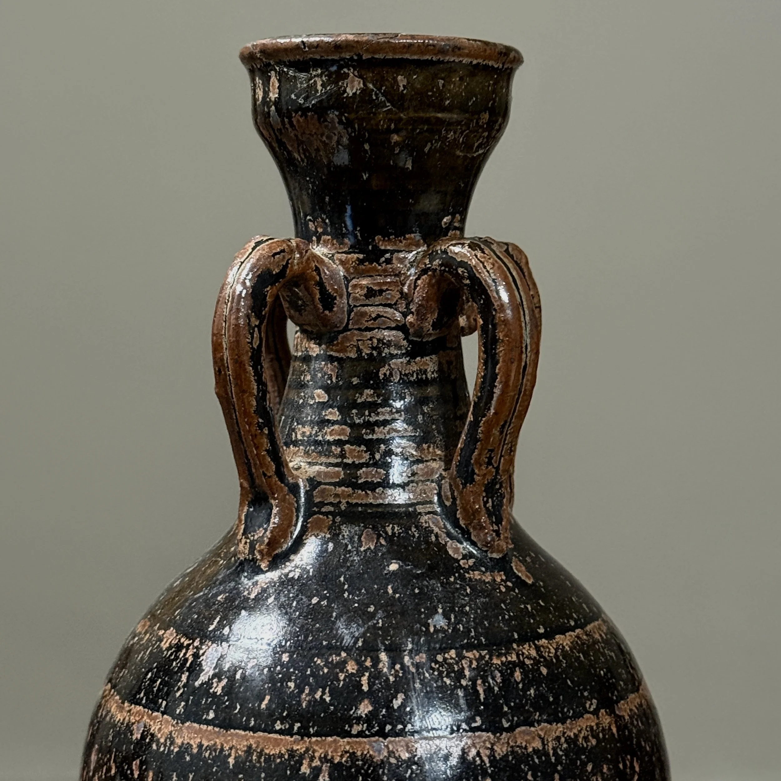 Close-up detail of mottled brown speckled glaze on antique four handled stoneware vessel, showing glaze texture