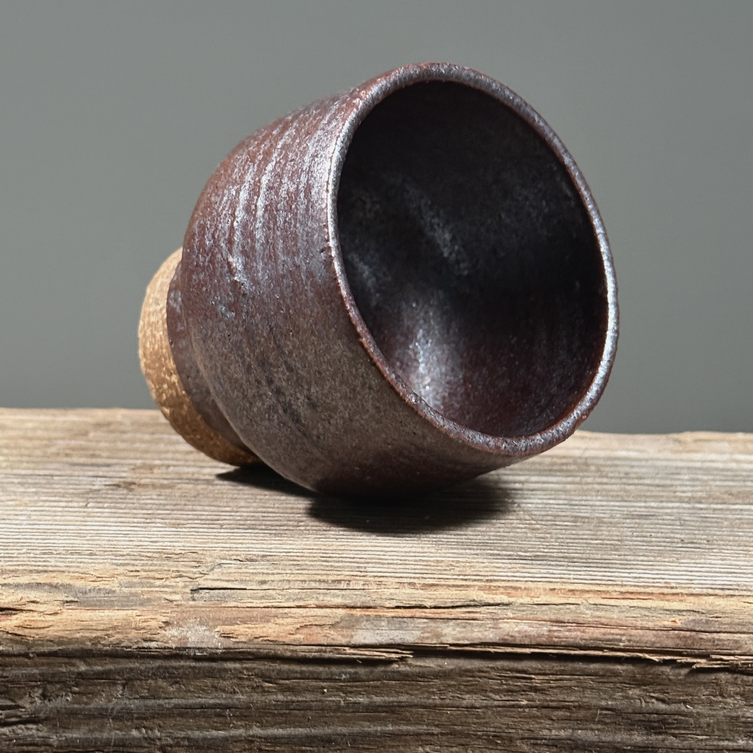 Maroon metallic yunomi cup. Deep maroon surface. Faint blue undertone visible at rim under light.