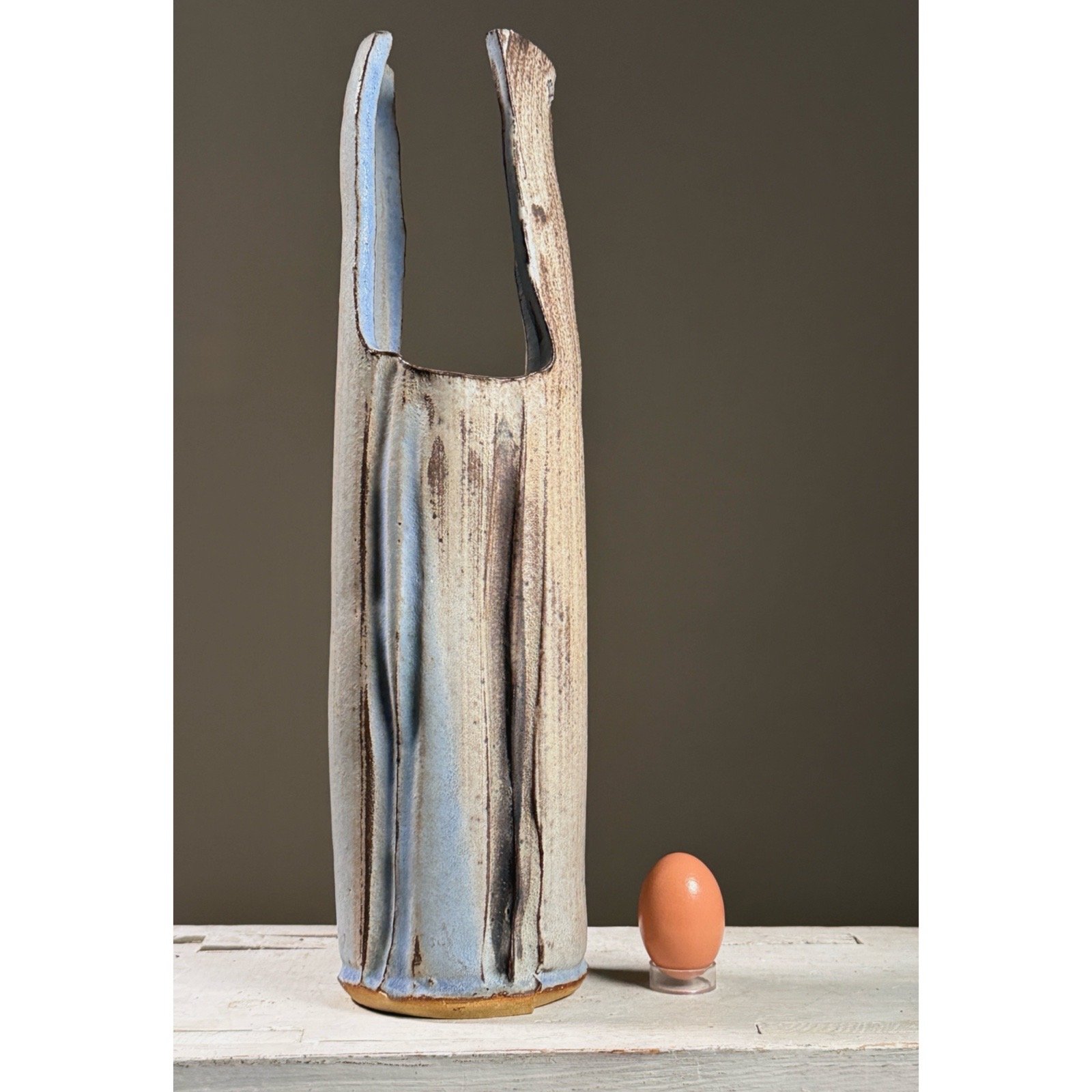 Full frontal view of a large vintage wood-fired ikebana vase by Seiko Kato Behr with egg for size reference.