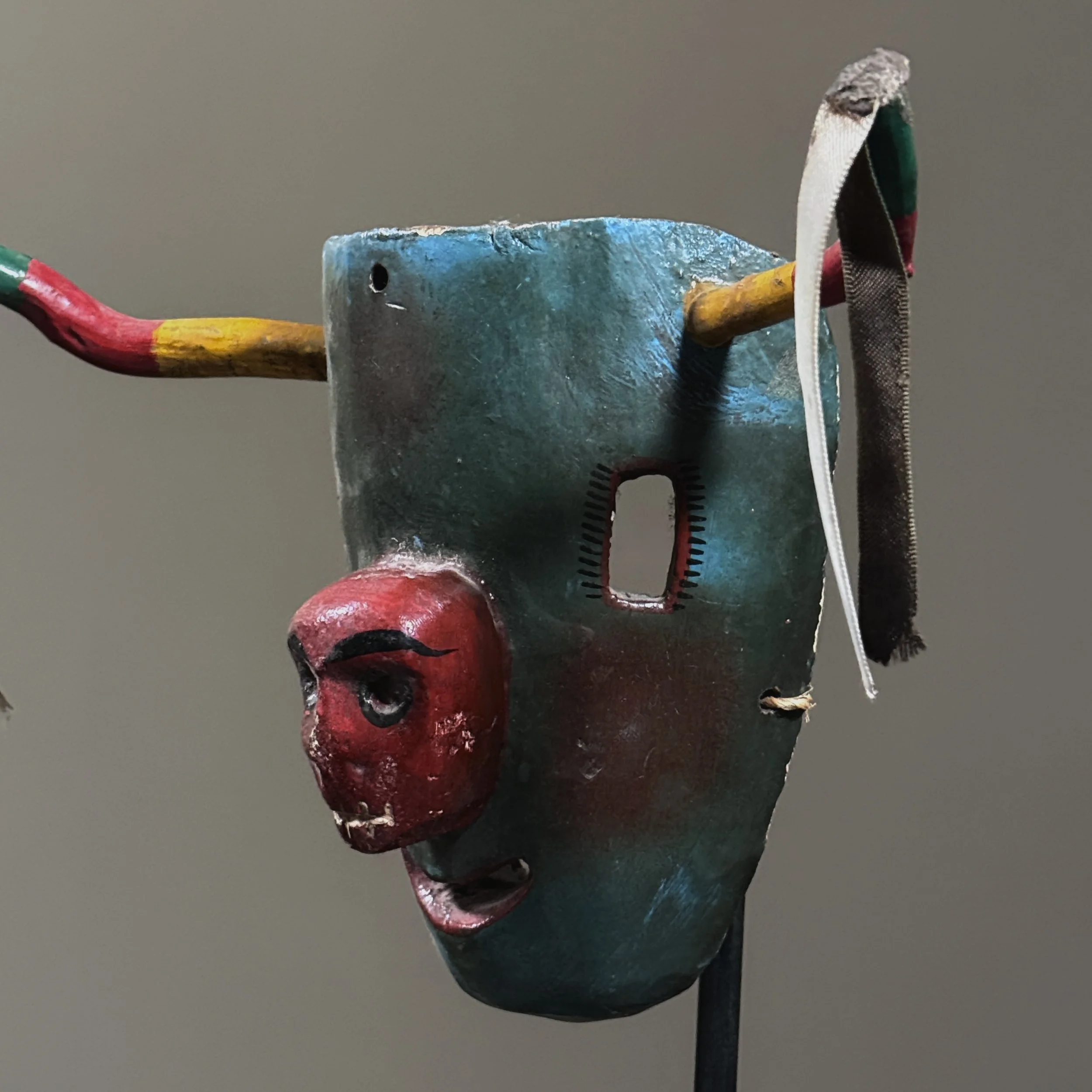 Side view of polychrome Mexican bull mask with red skull motif