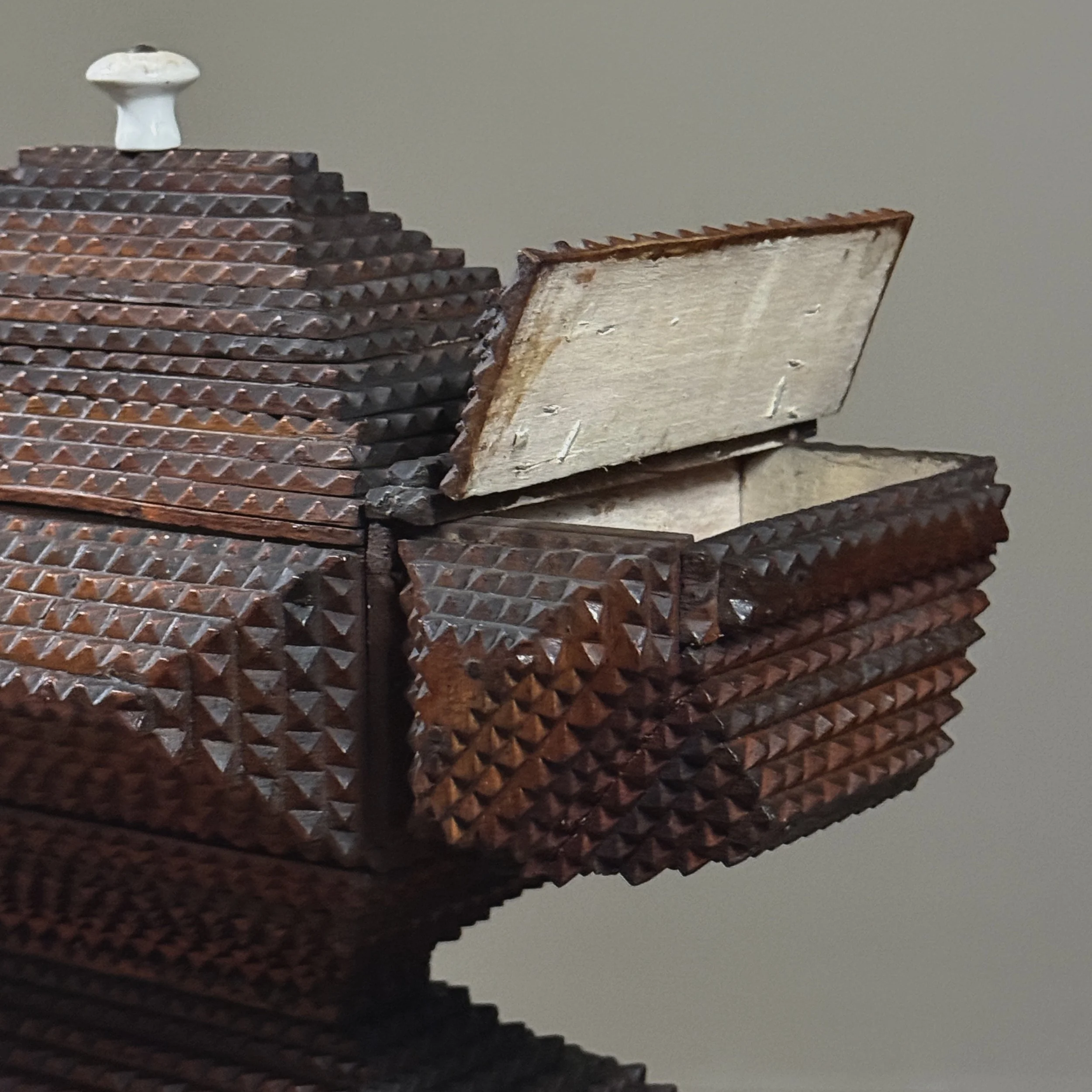 Close-up of hinged flip-top side compartment with carved decoration