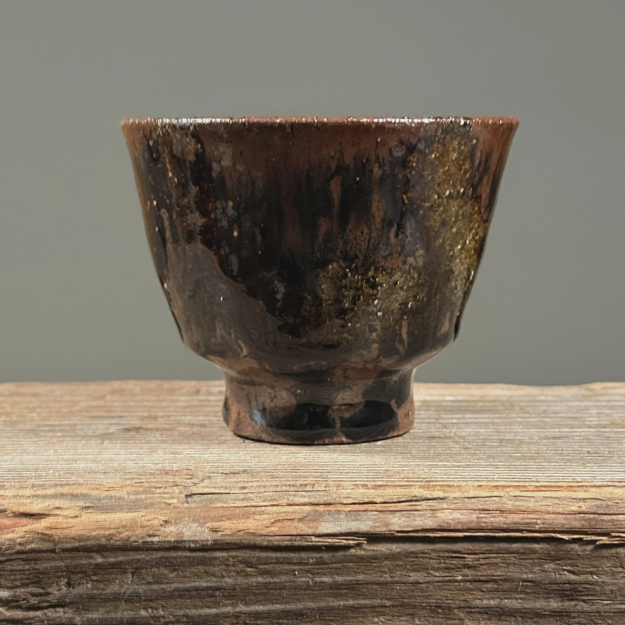Brown glossy drip yunomi cup. Vertical glaze drips on warm brown stoneware. Unglazed foot ring exposed.