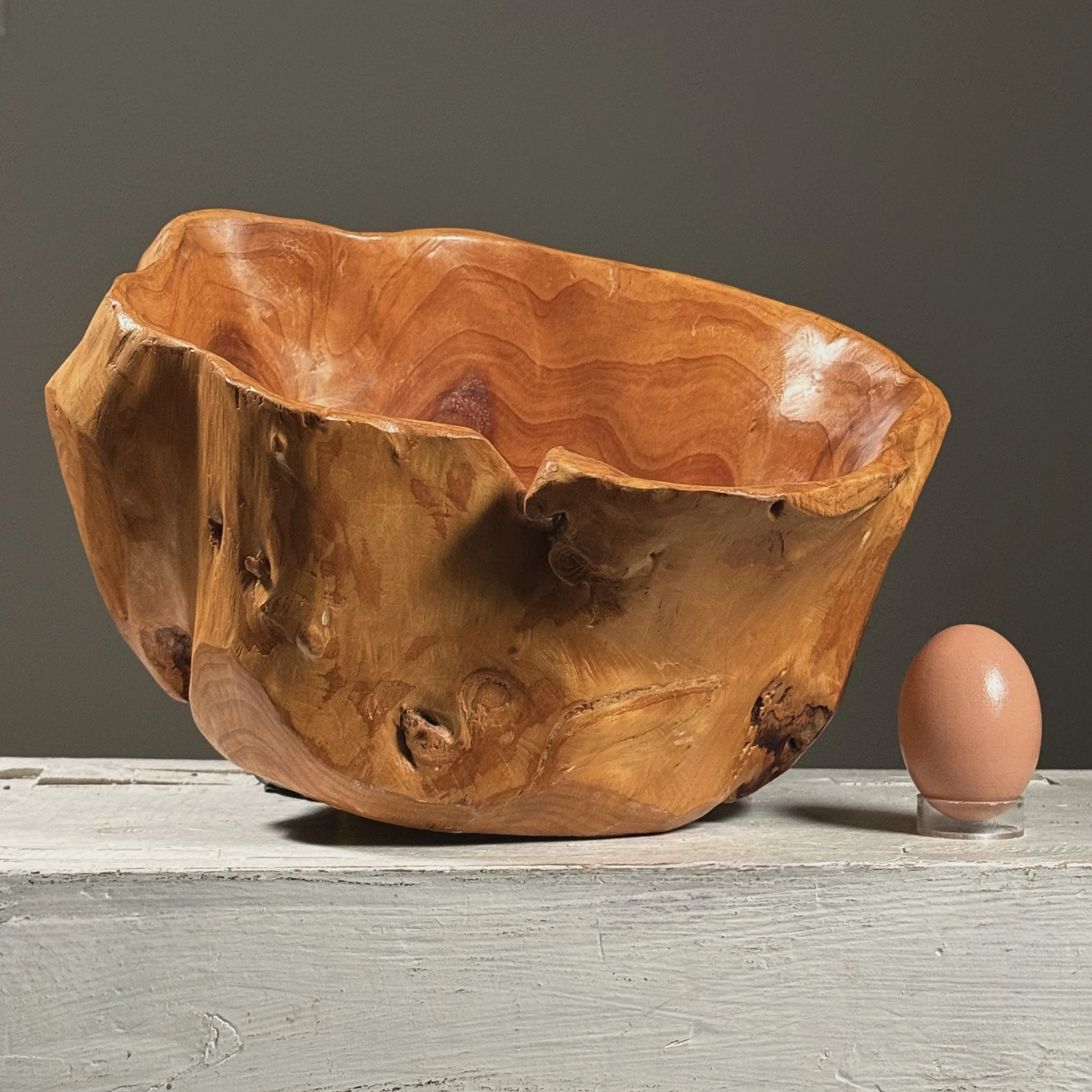Full frontal view of a vintage hand-carved modernist root bowl with live edge exterior with egg for size reference.