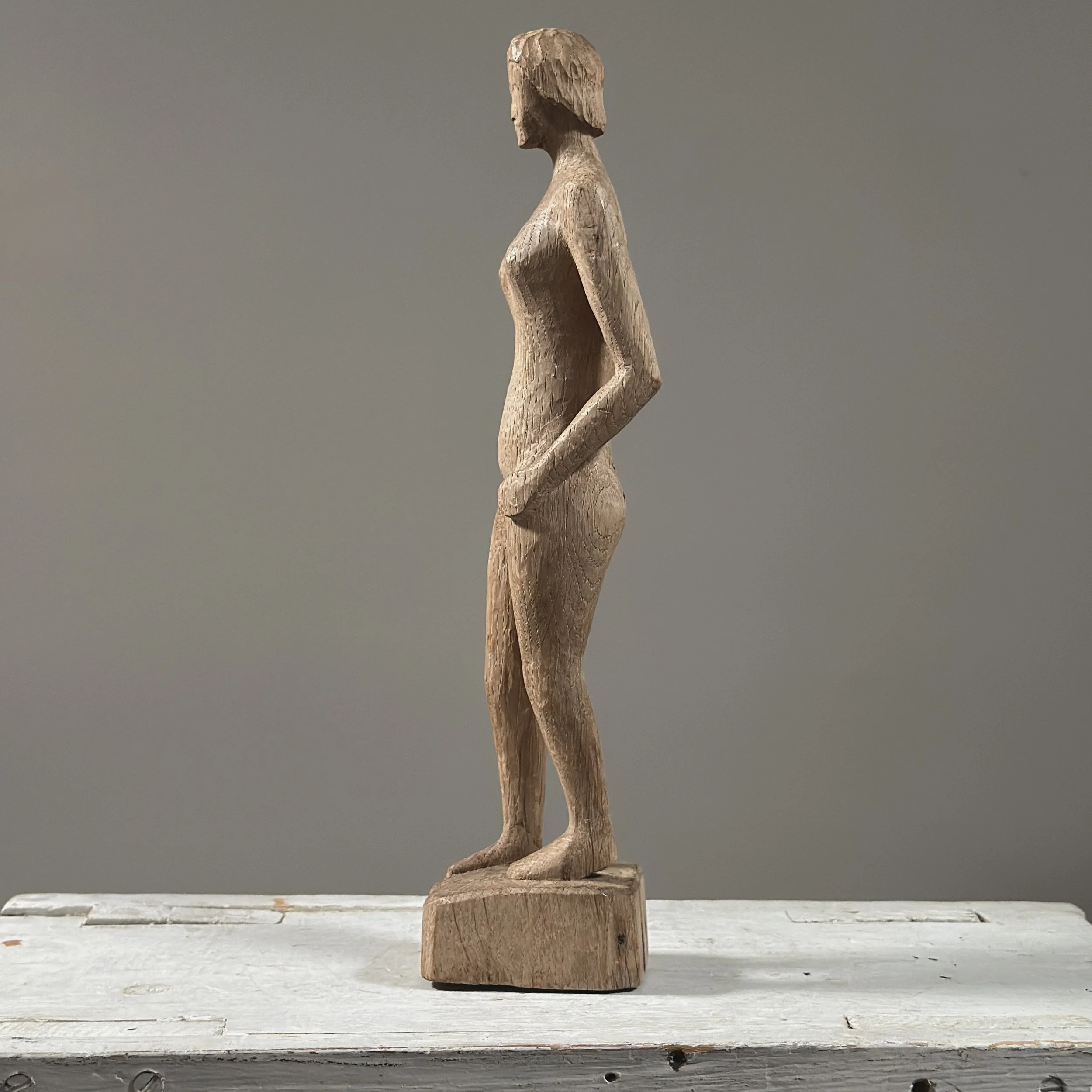 Side profile view of vintage hand carved wood modernist female nude, raw wood, small base