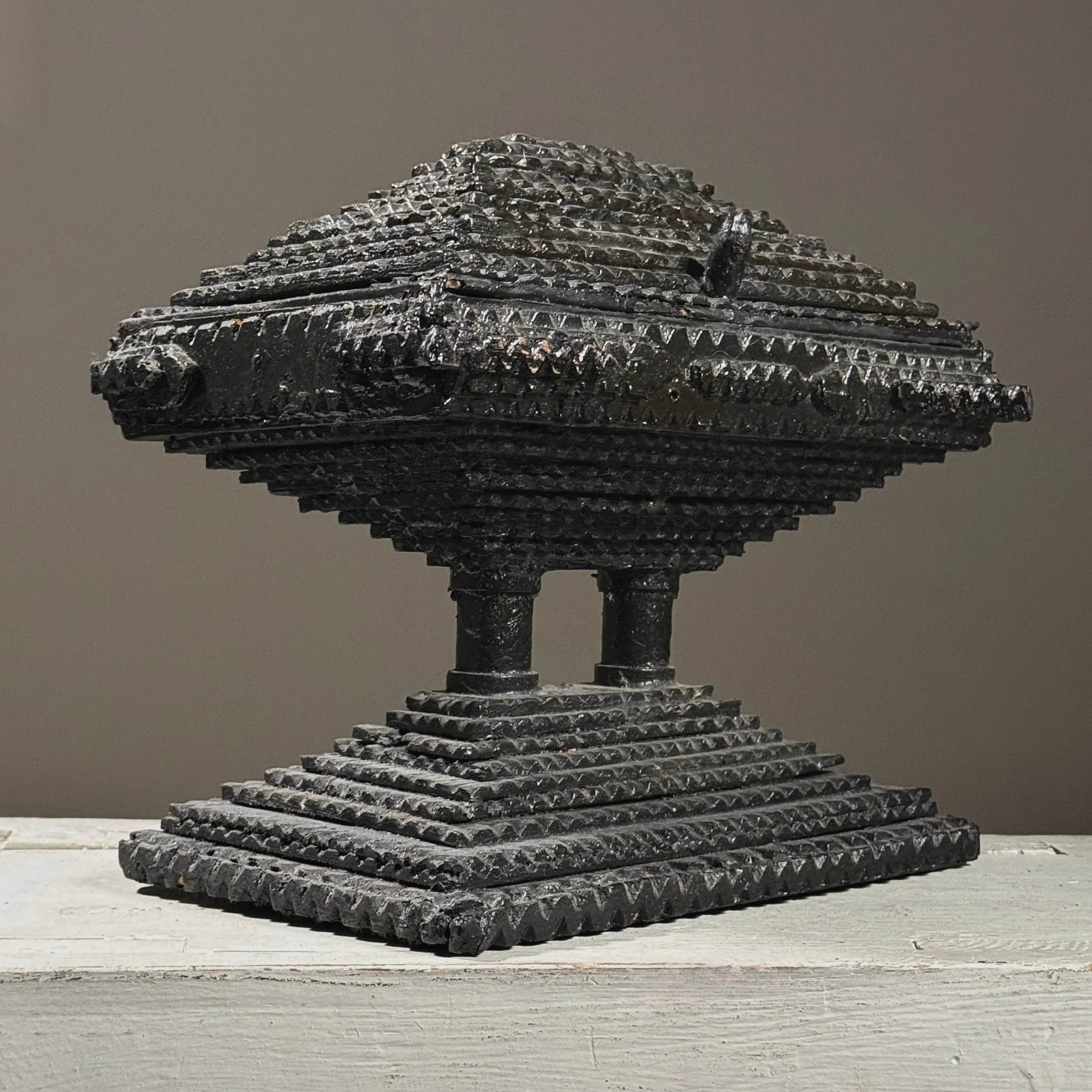 Three-quarter view of a two-tiered tramp art box showing layered chip-carved construction