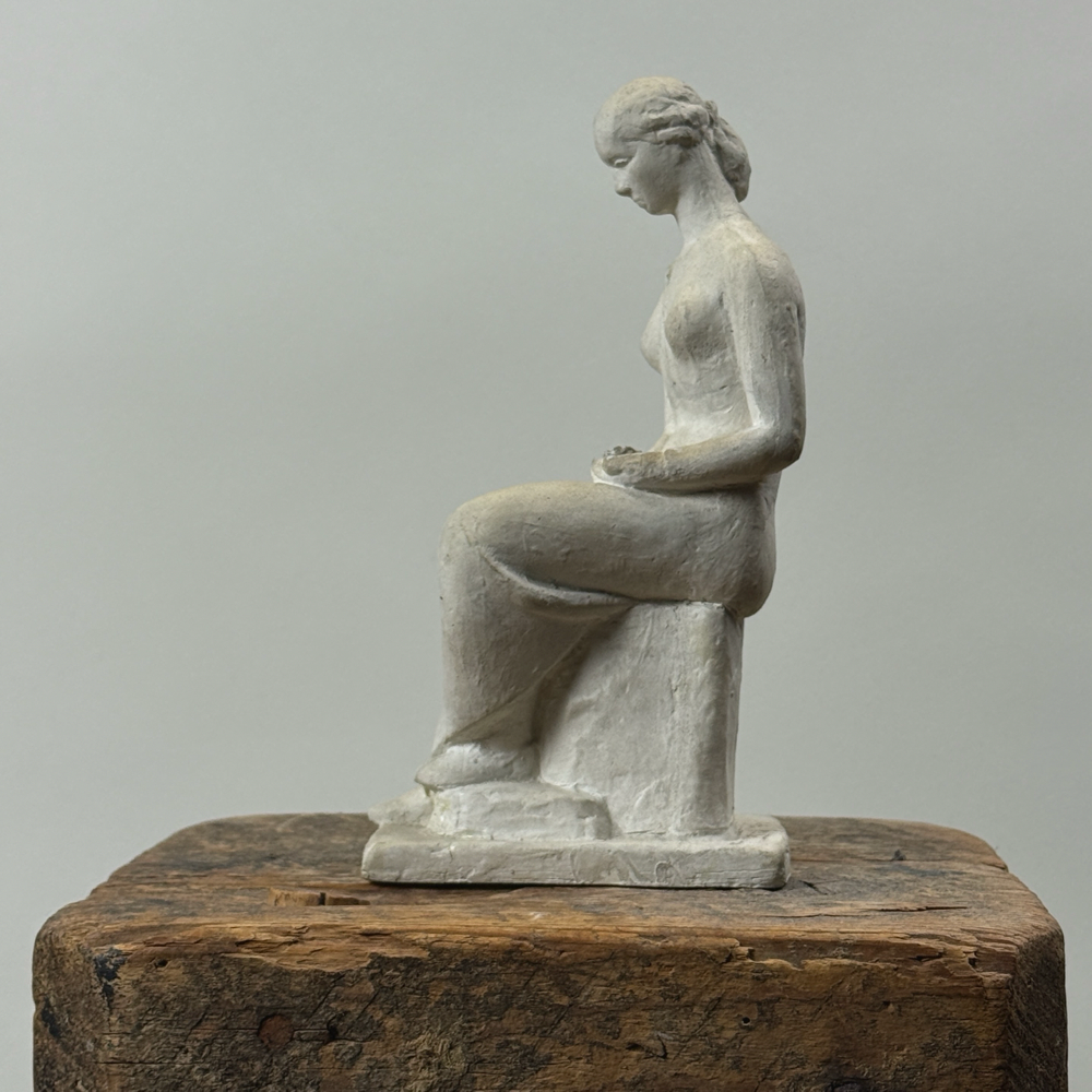 Vintage painted plaster statue of seated woman. Signed Rudy on back. 8.25 inches high.