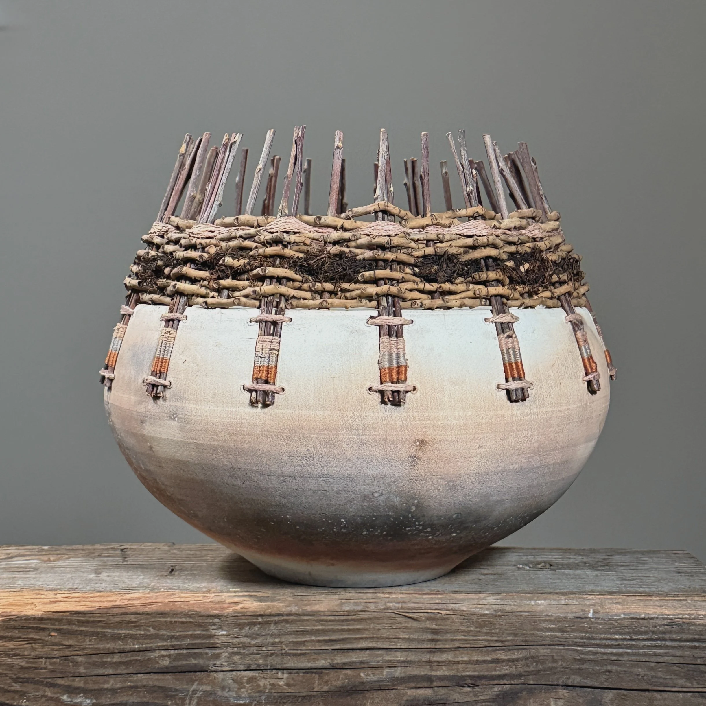 Raku fired ceramic vessel with woven reed rim