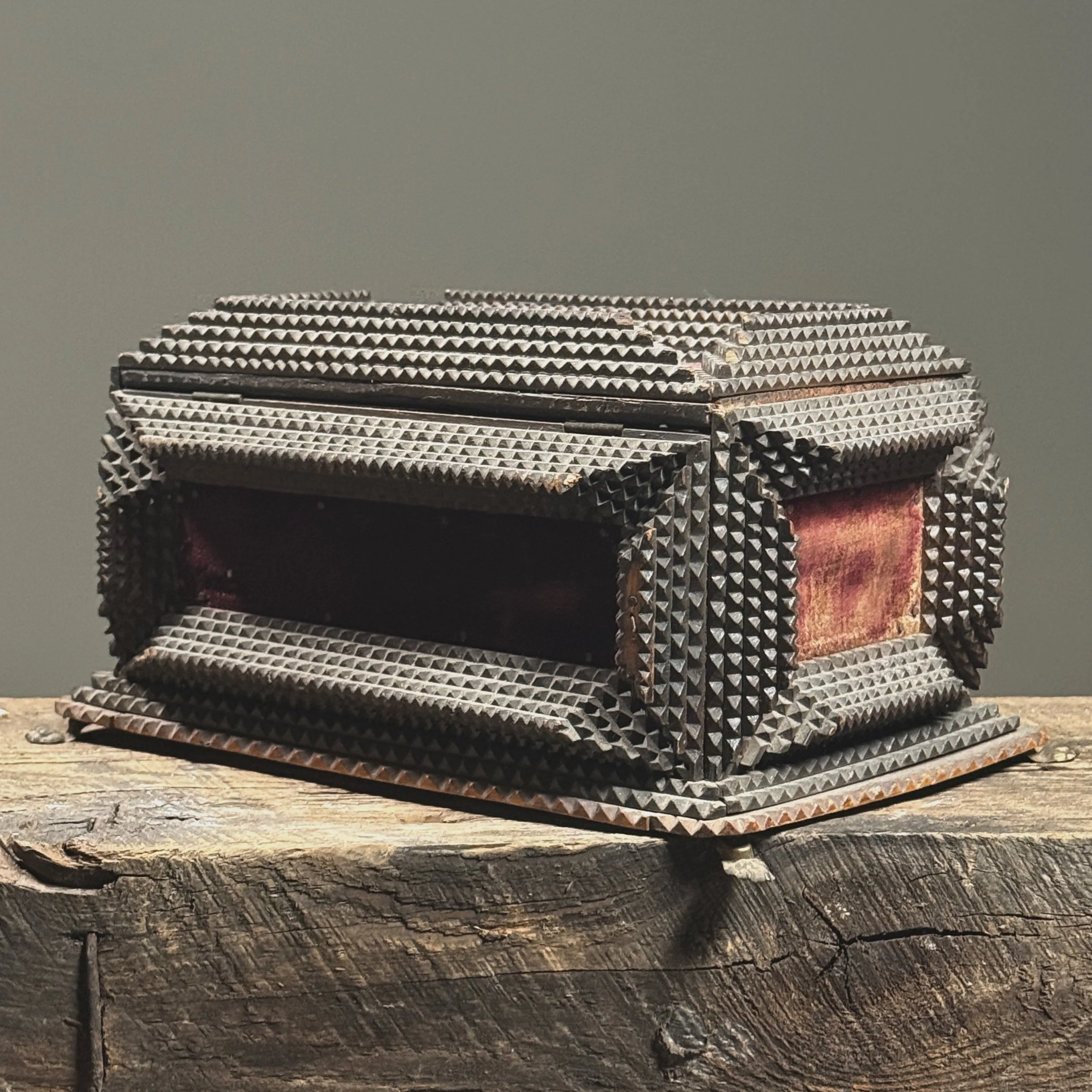 Three-quarter view showing chip-carved wood and velvet inserts.