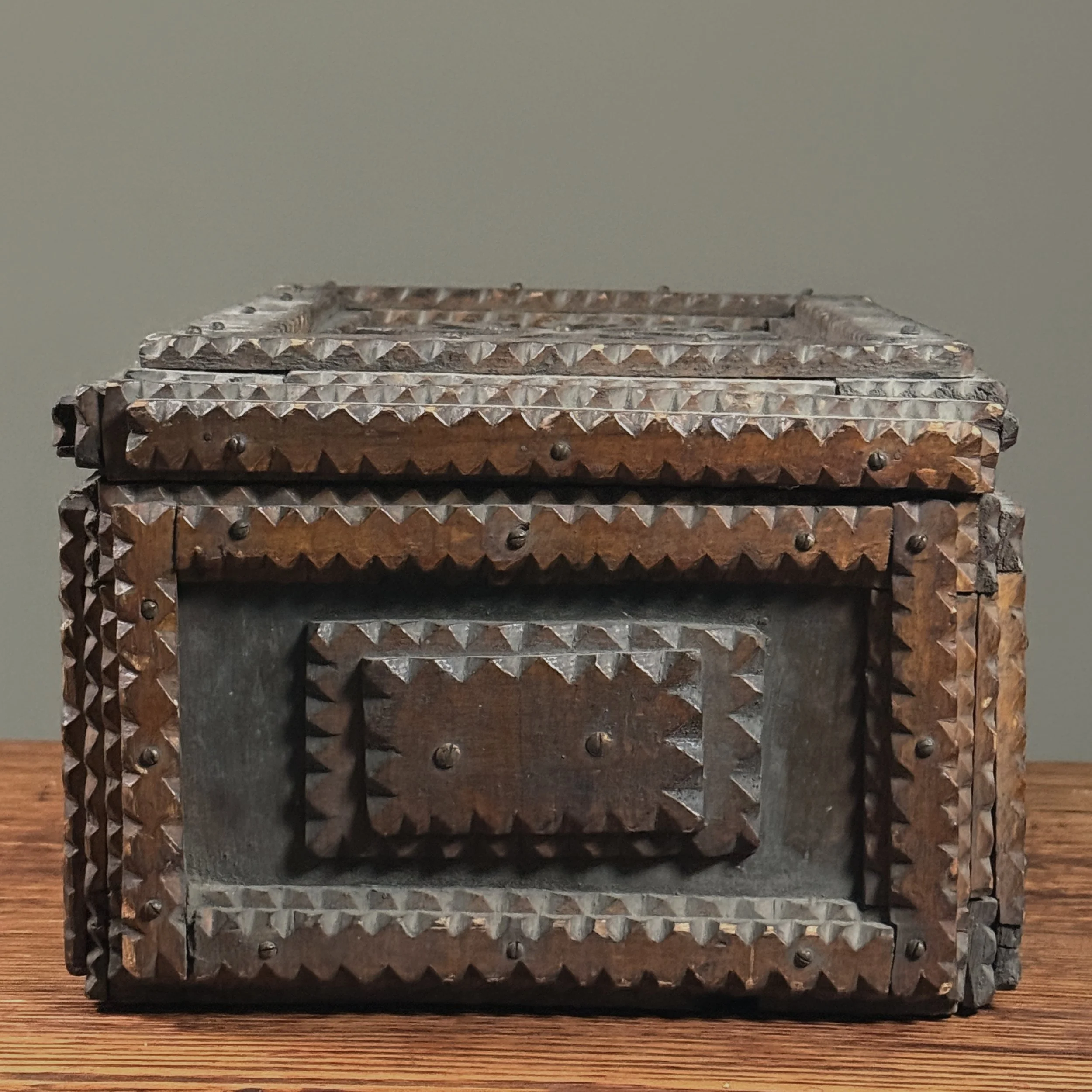 View of the tramp art chest from the side, showing the depth of the carving.