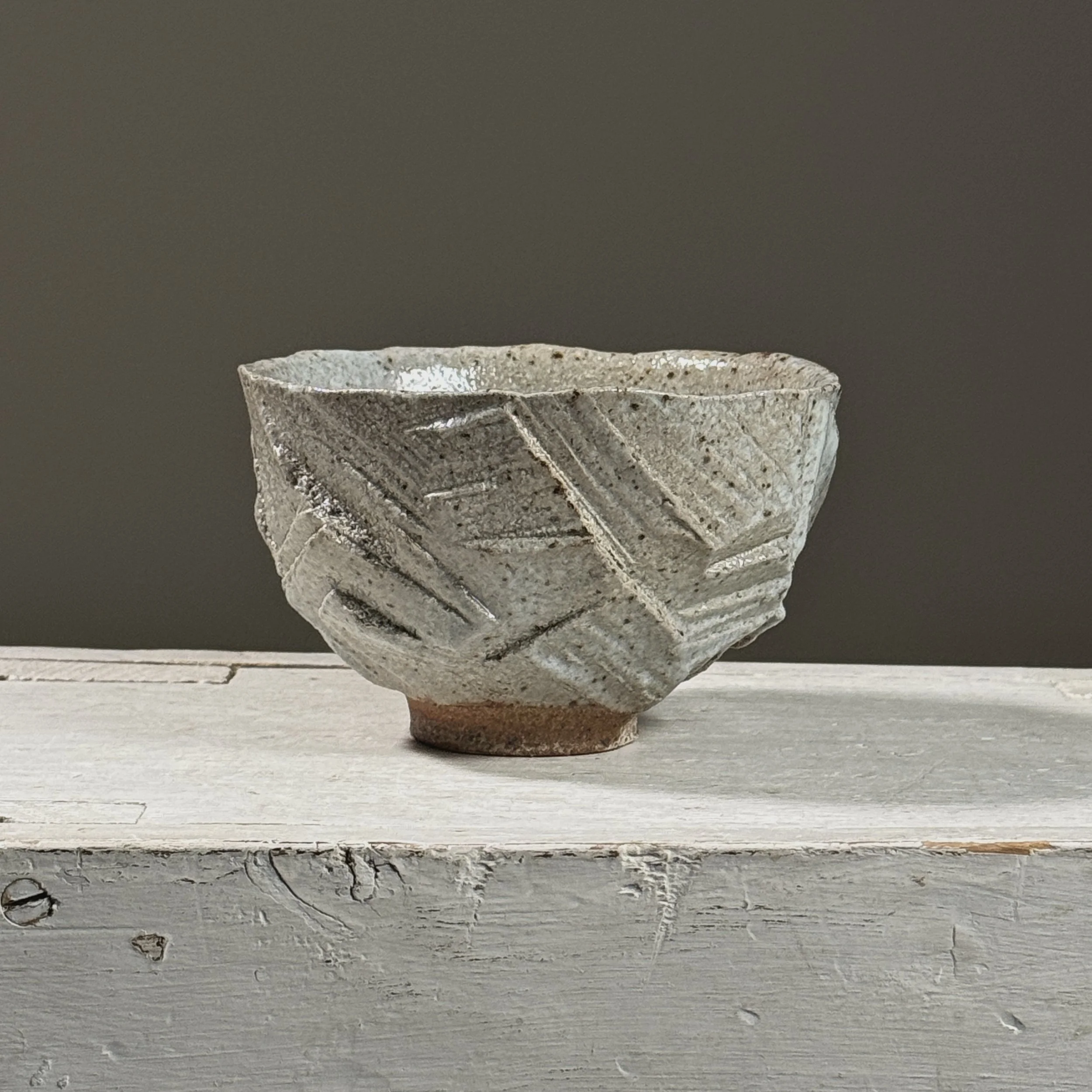 Front view of a vintage Brutalist geometric carved ceramic footed bowl.