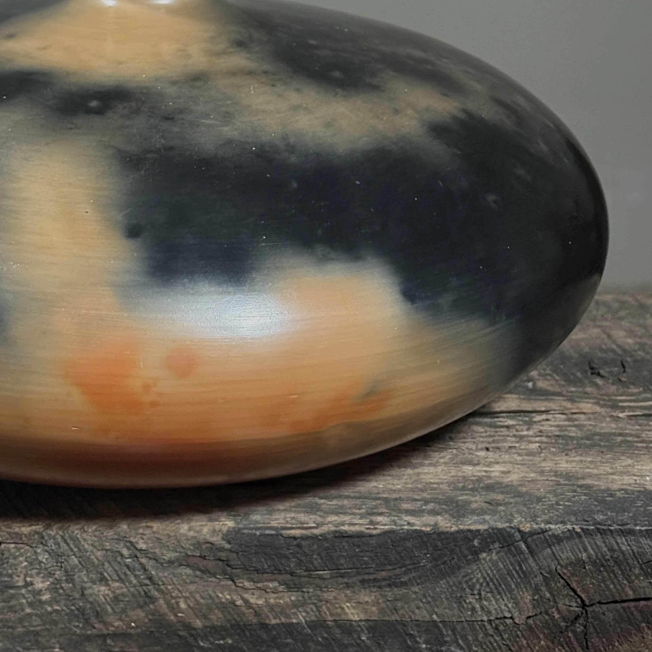 Large round seed pot with mottled orange and black firing effects.