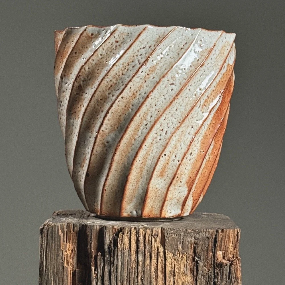 Front view of a vintage Japanese faceted swirl vase with Shino glaze.