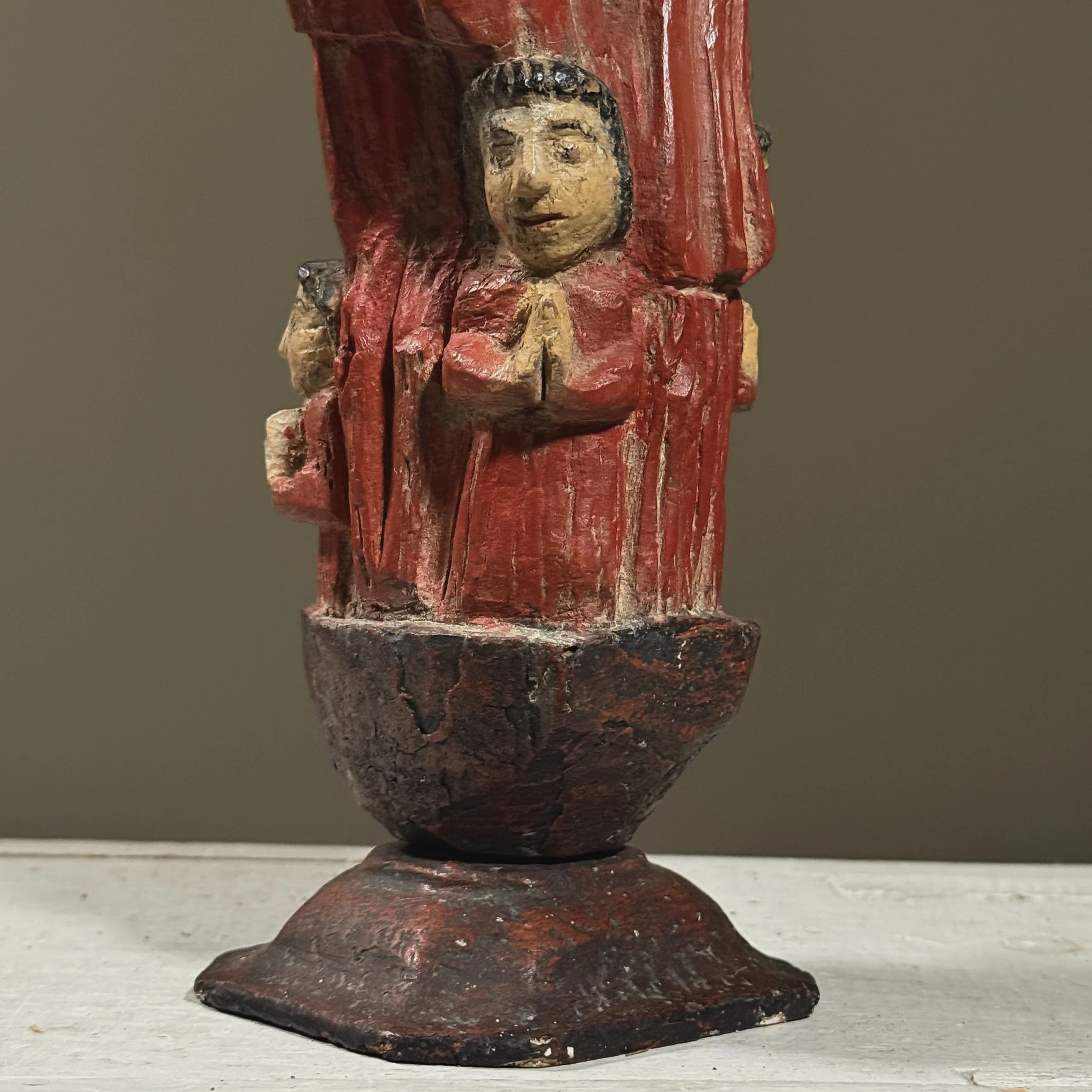 Lower row of five children in red robes on Santos sculpture