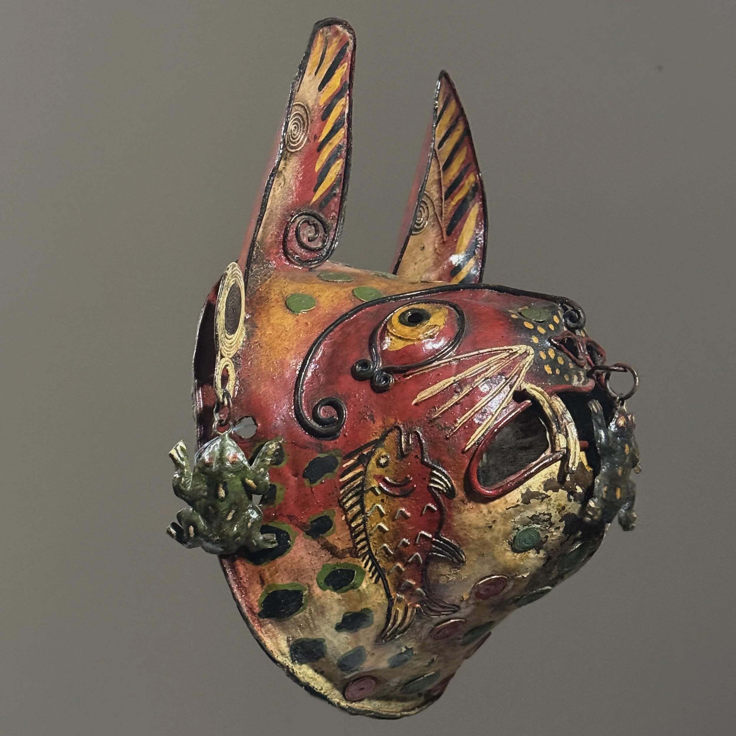Side angle of polychrome metal Guerrero tigre mask with frog figures