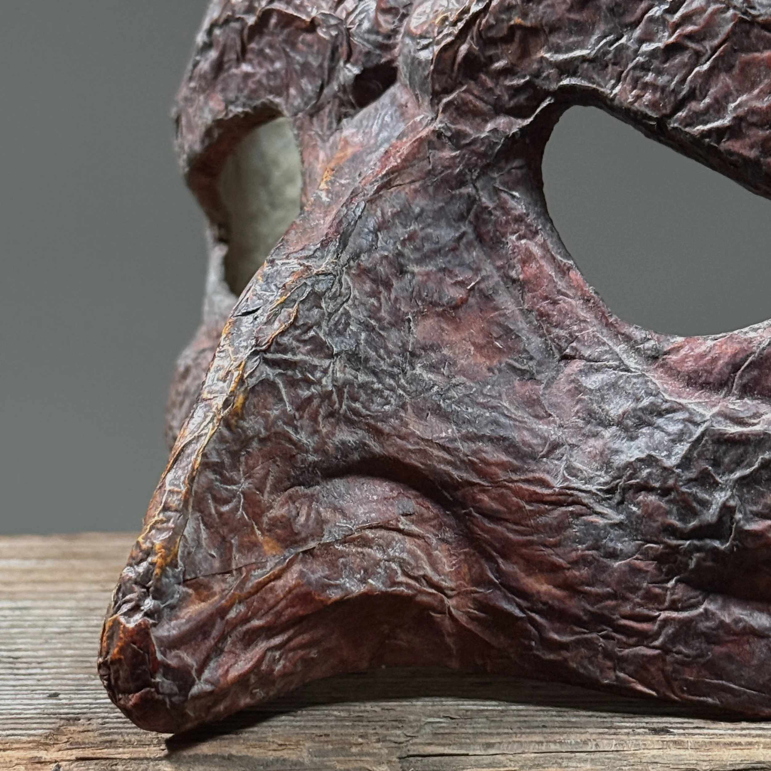 Close-up of red papier-mâché surface texture and craquelure.