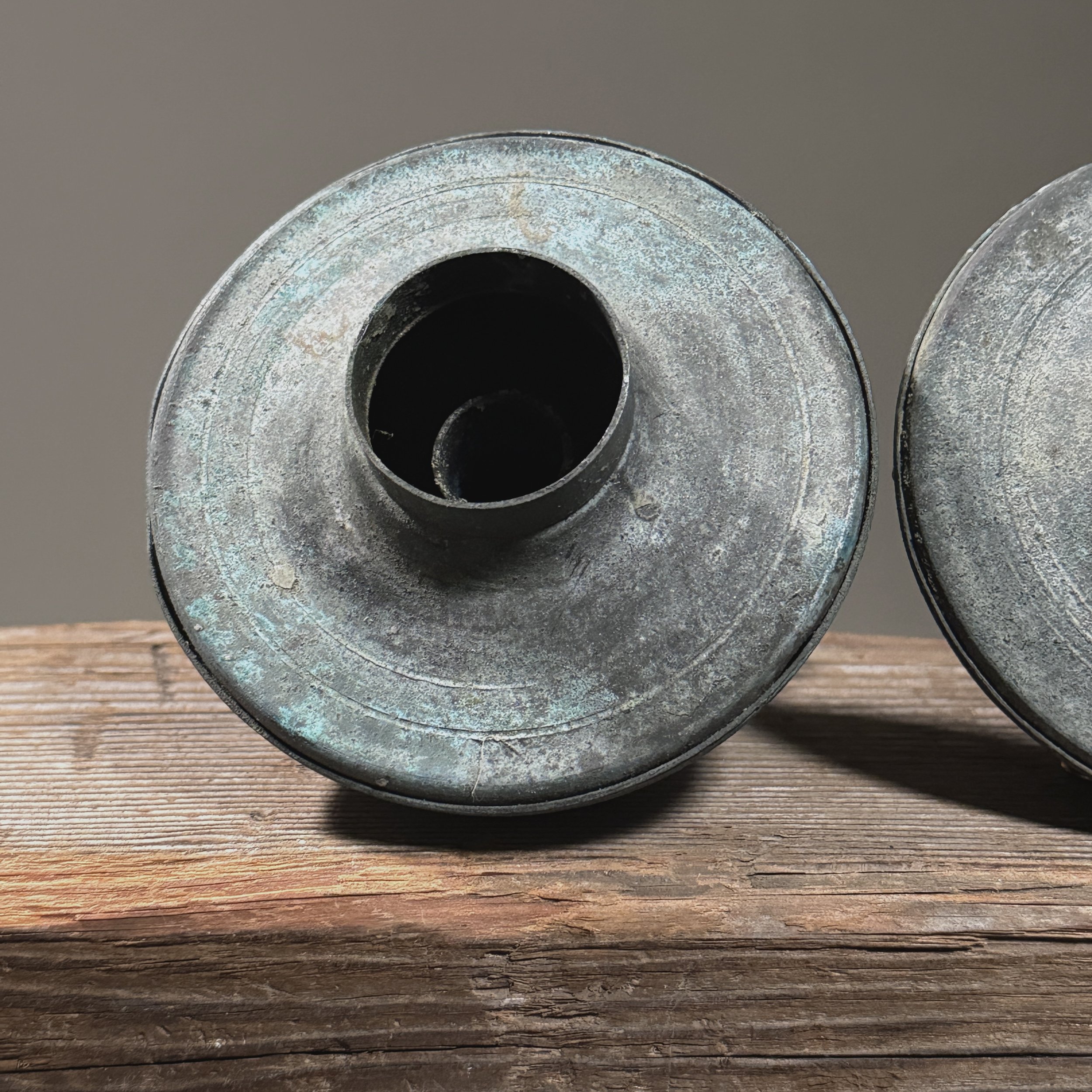 Close-up of textured surface on one Brutalist candle holder showing layered blue-green patina.
