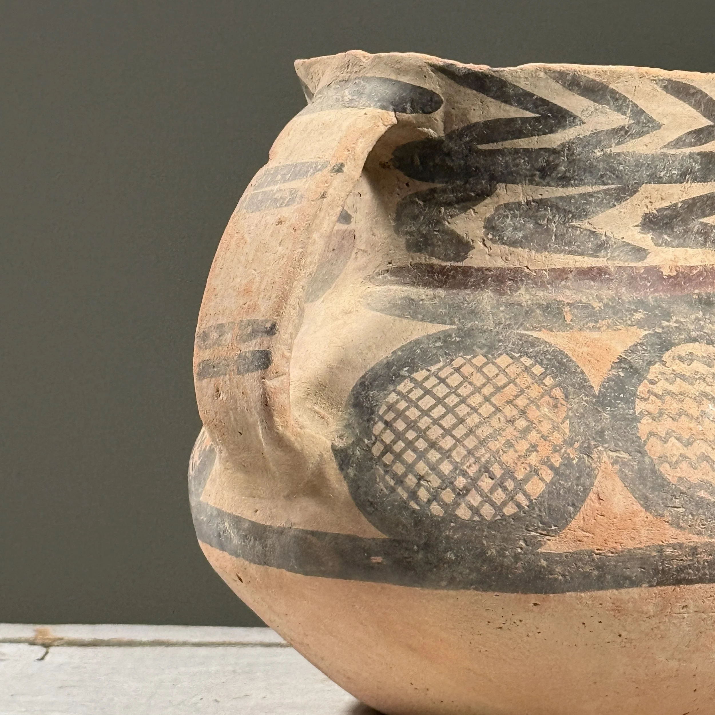 Close-up detail of zigzag and concentric band patterns painted on a vintage Chinese ceramic vessel