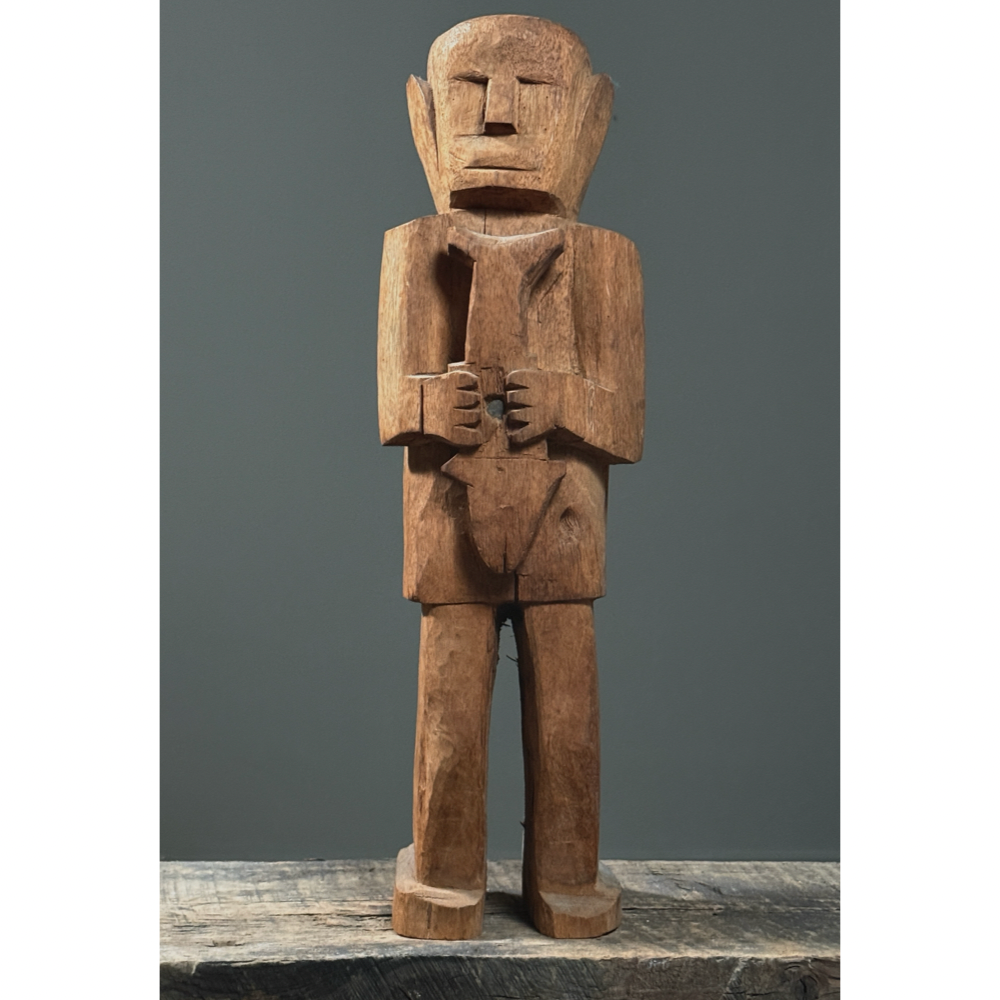 Front view of hand-carved wood folk art figure of man holding a fish