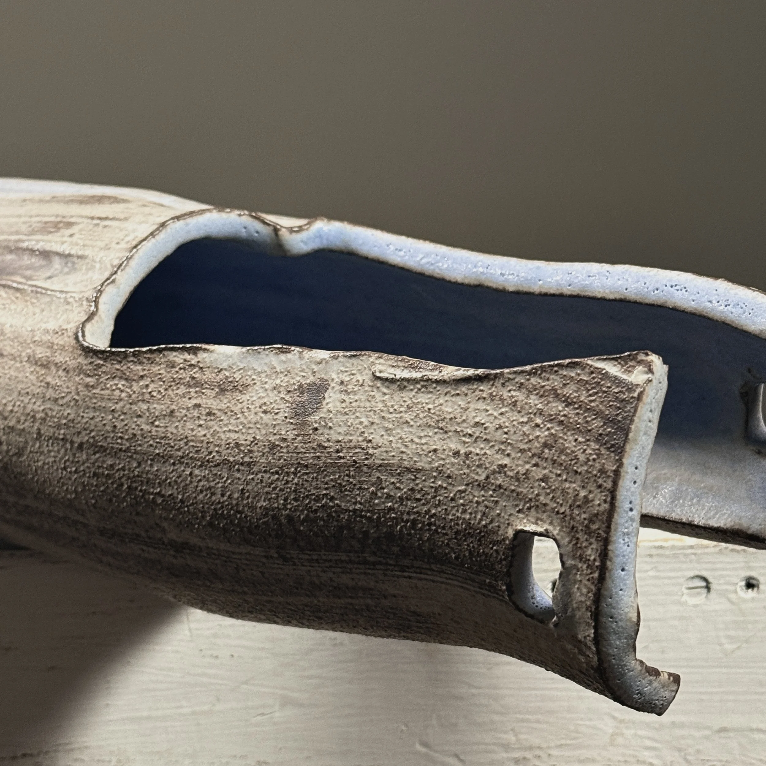 Close-up detail of wood-fired surface effects including pale blue streaks and speckled grey markings