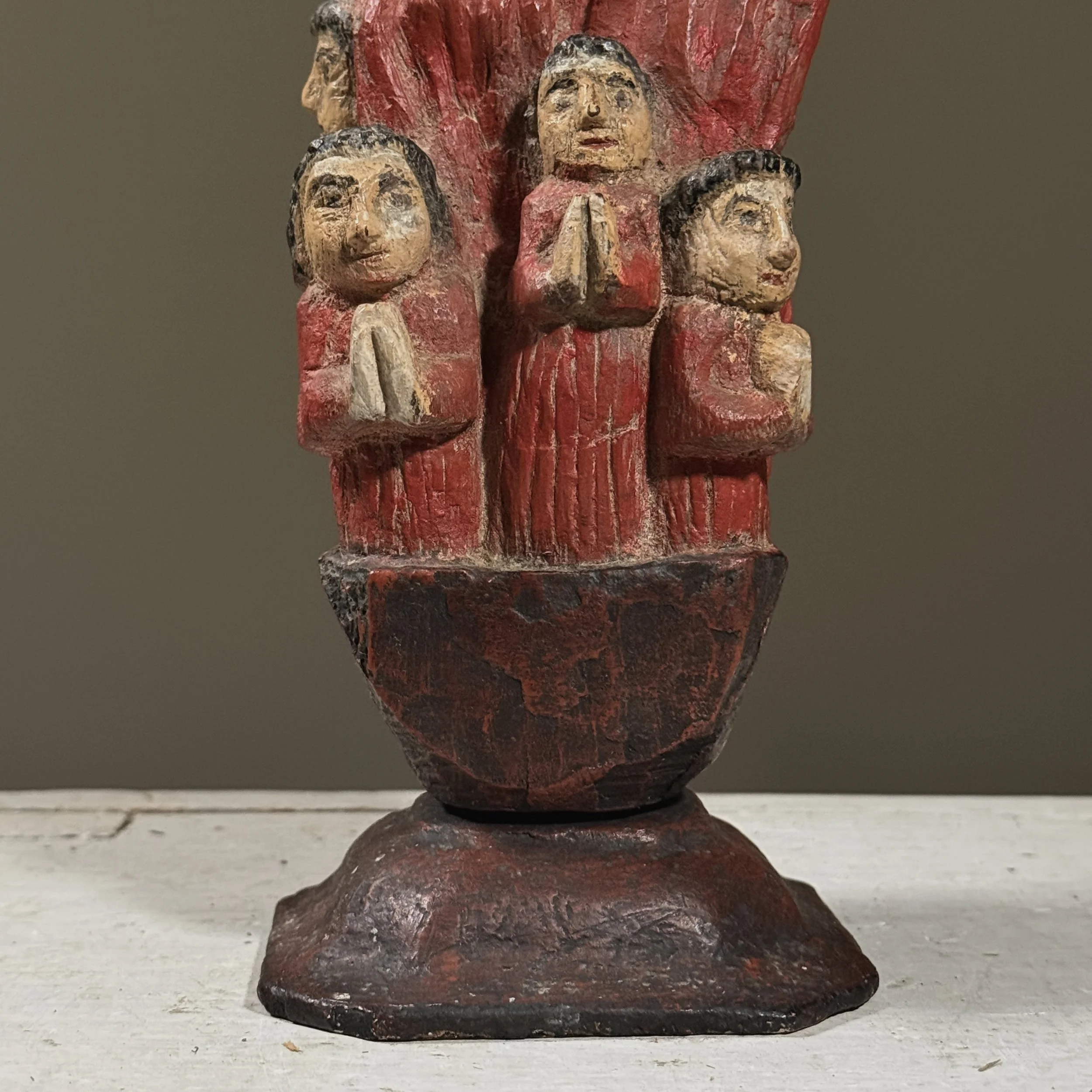 Lower row of five children in red robes on Santos sculpture