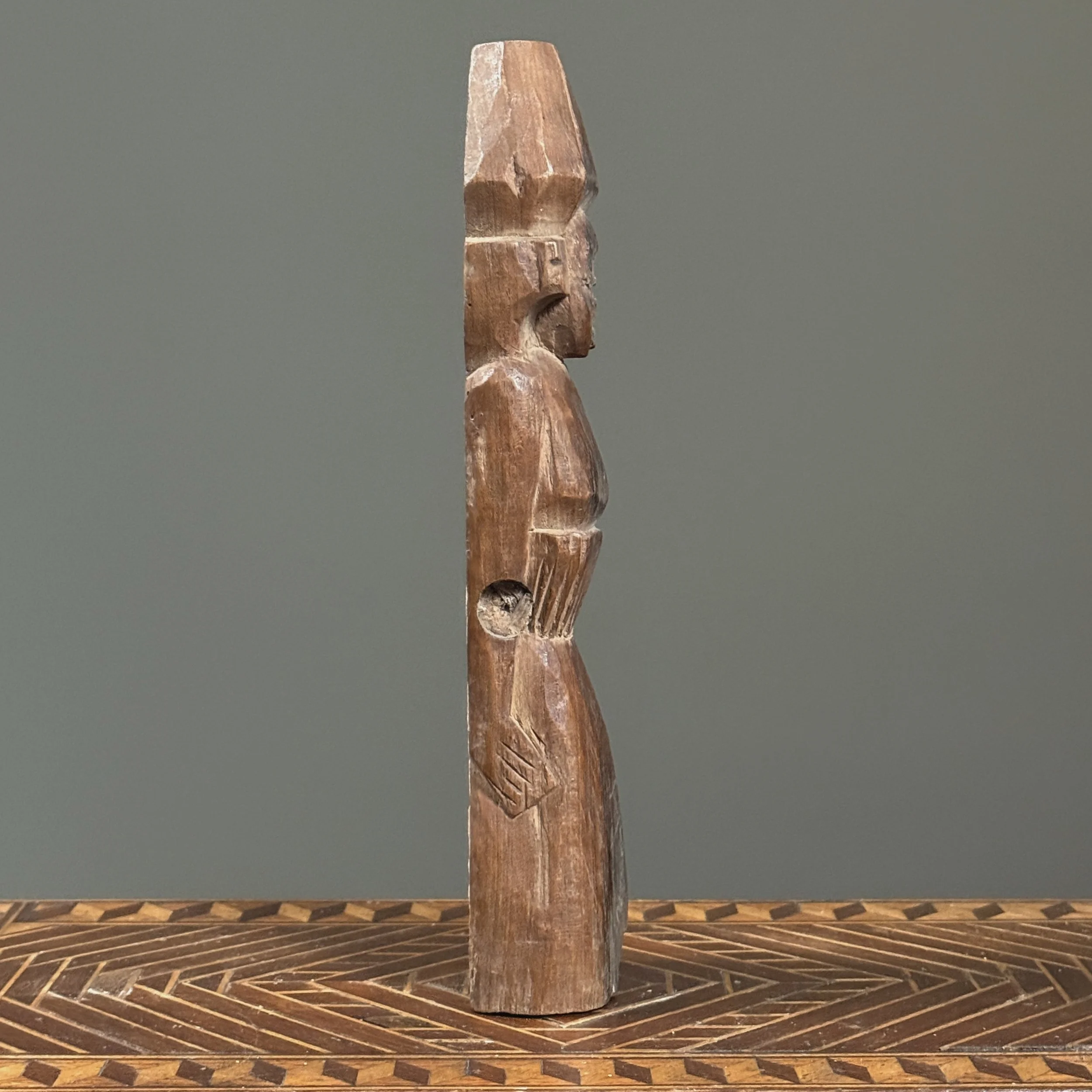 Flat-backed brown wooden female figure from Southeast Asia, side view.